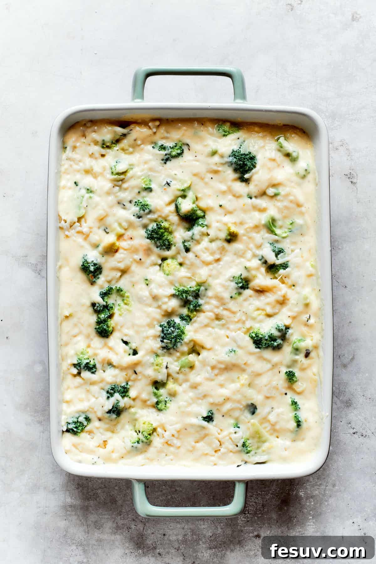 From-scratch Broccoli & Rice Casserole folds tender broccoli and fluffy white rice into a gorgeously creamy three-cheese sauce. Broccoli and rice are mixed into cheese sauce in a pan for broccoli & rice casserole.