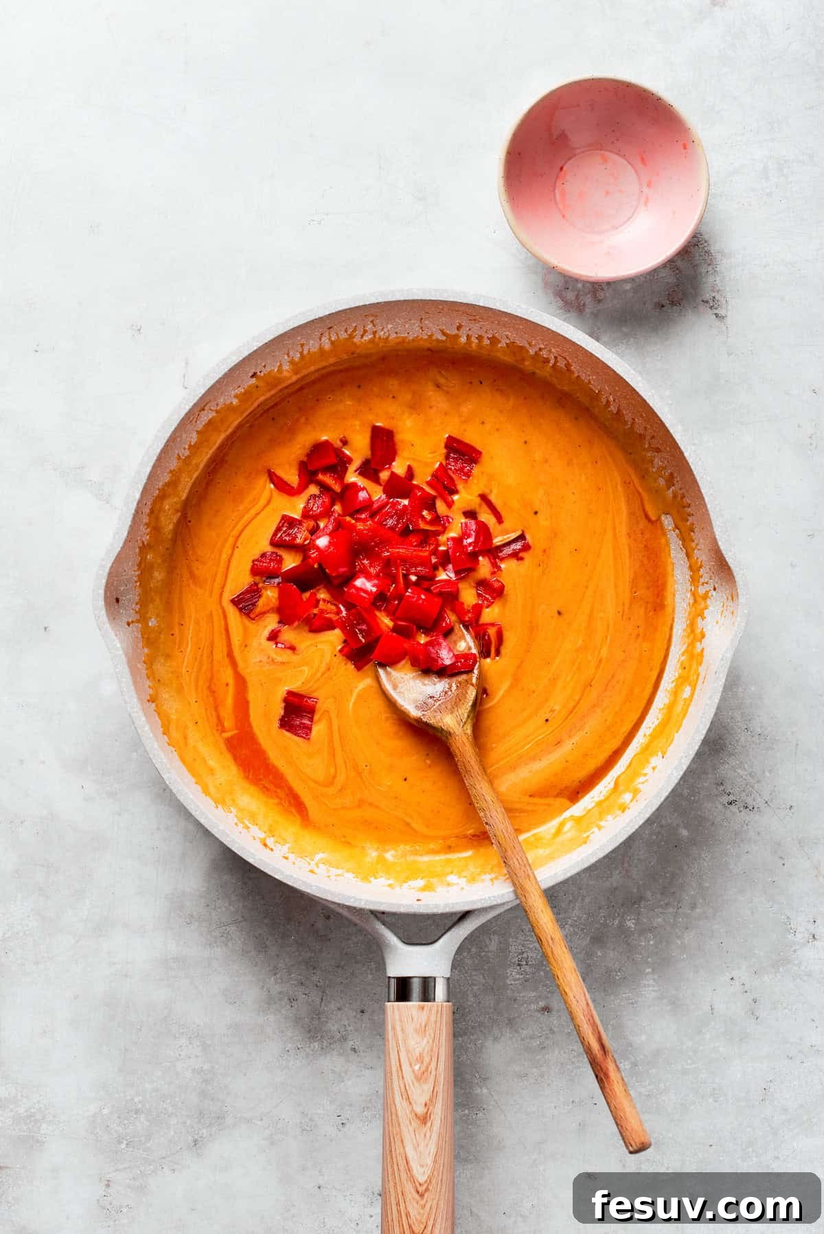Chopped bell peppers are added to tomato sauce.