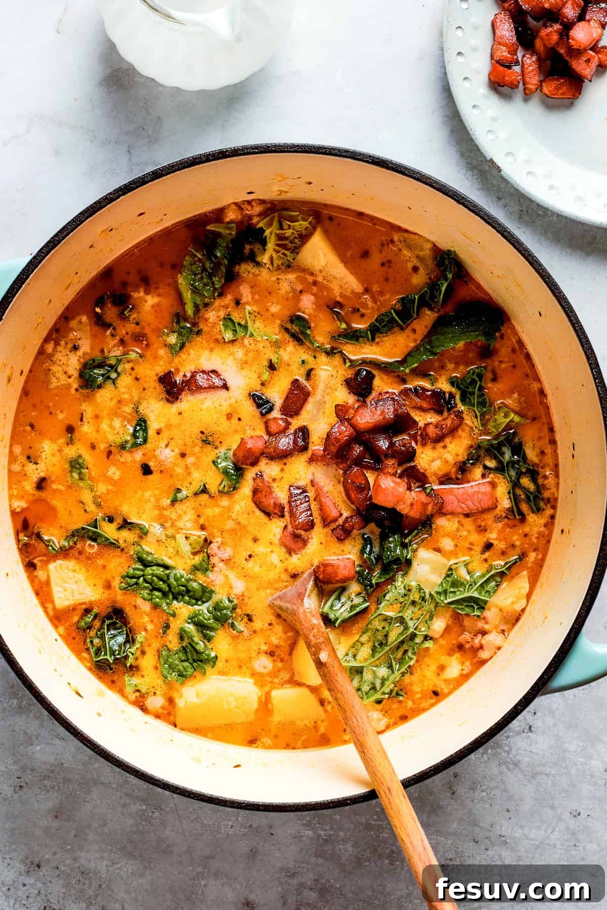 My Zuppa Toscana recipe features Italian sausage, bacon, potatoes, and kale in a savory broth. It’s an easy copycat version of the Olive Garden classic! An inviting overhead shot of Zuppa Toscana simmering in a large pot, showcasing its rich texture and colorful ingredients.