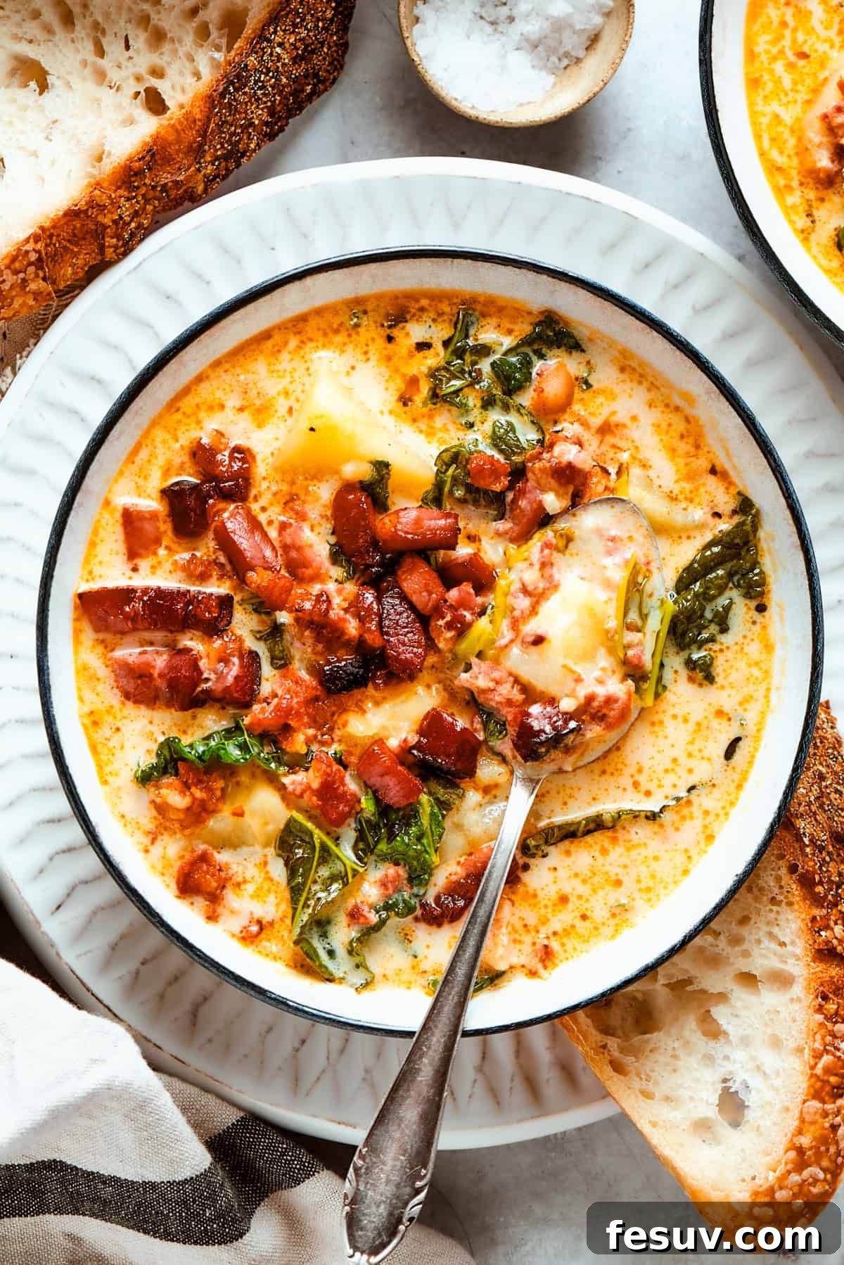 My Zuppa Toscana recipe features Italian sausage, bacon, potatoes, and kale in a savory broth. It’s an easy copycat version of the Olive Garden classic! A beautifully presented bowl of Zuppa Toscana, garnished with extra crumbled bacon, invitingly warm and ready to savor.
