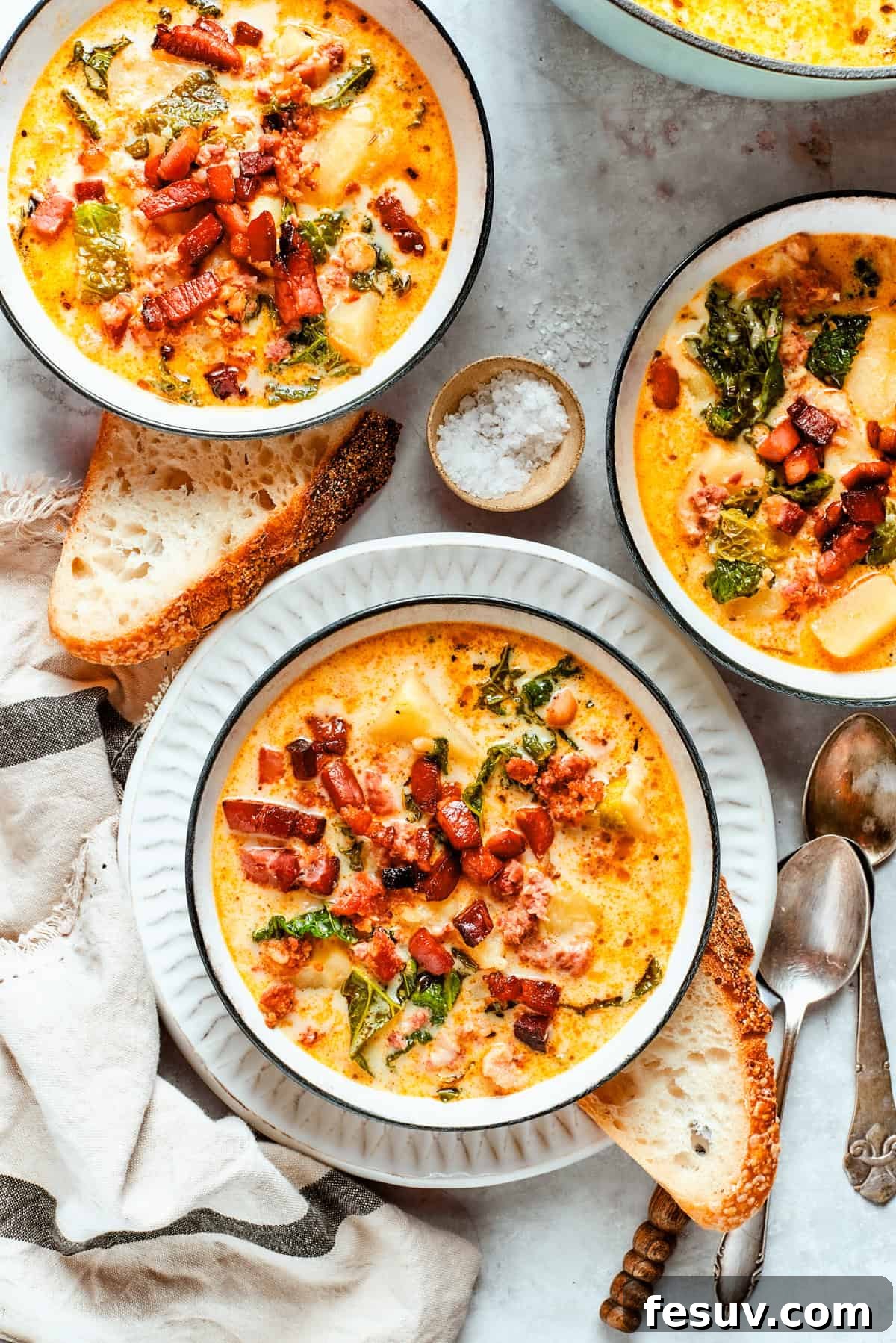 Creamy Tuscan Sausage and Kale Soup 2 Three steaming bowls of Zuppa Toscana, beautifully garnished with crumbled bacon, arranged on a rustic table.