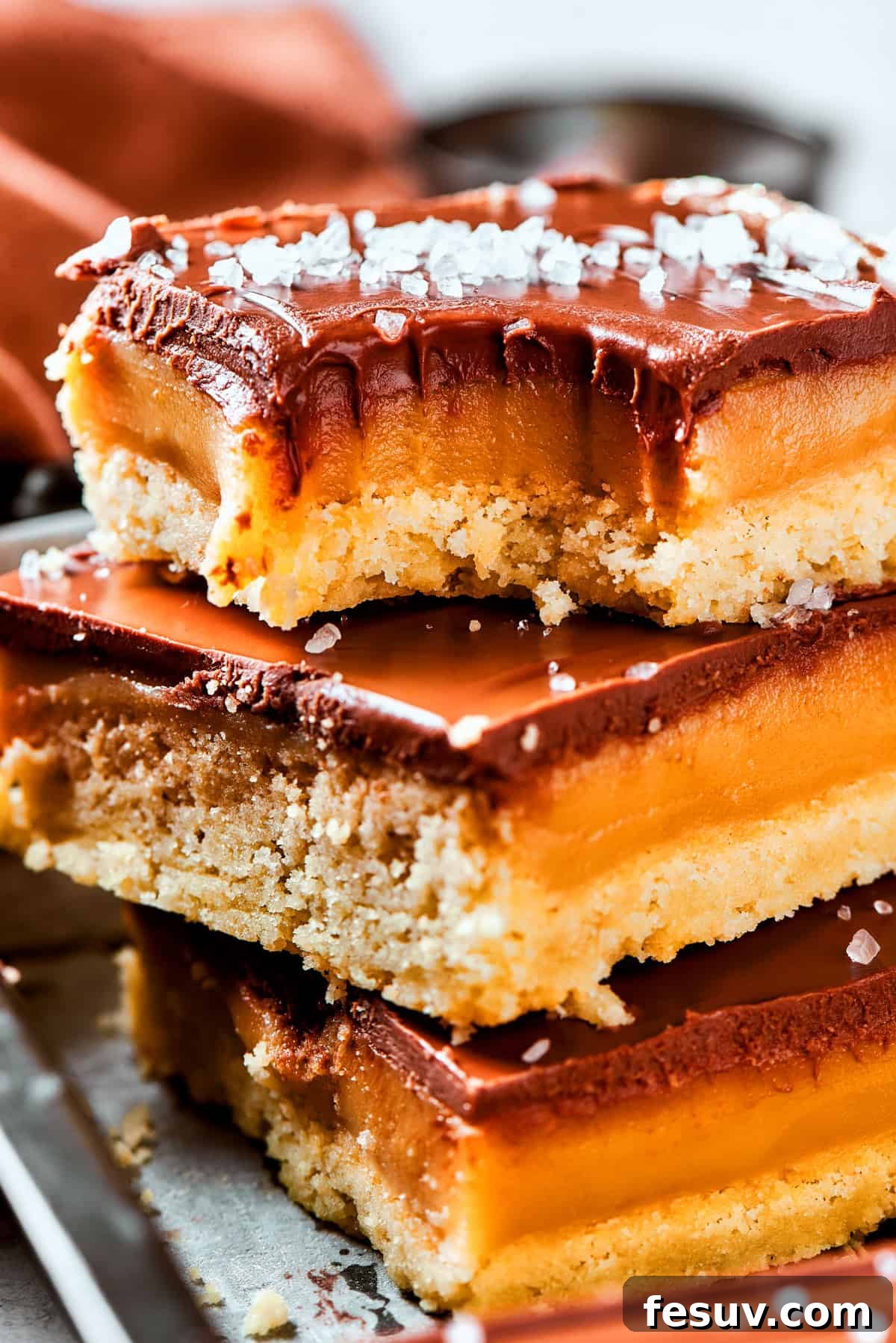 A stack of millionaire bars with a bite taken out of the top bar, showcasing the three distinct layers.