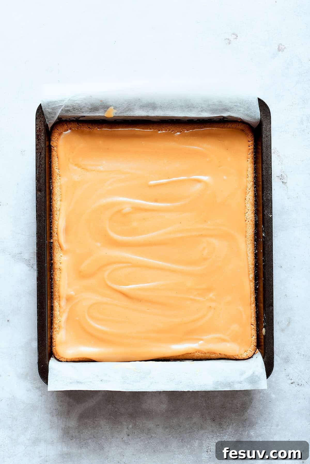 Caramel sauce is poured evenly over the baked shortbread crust.