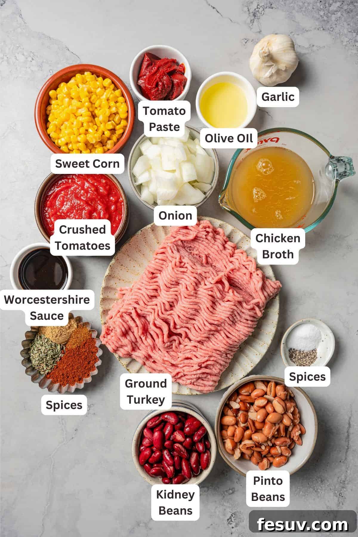 The BEST turkey chili recipe with juicy ground turkey, veggies, beans, and the perfect blend of spices. Great for weeknights and game days! Turkey chili ingredients with text labels overlaying each ingredient, showing fresh produce and canned goods laid out on a wooden surface.