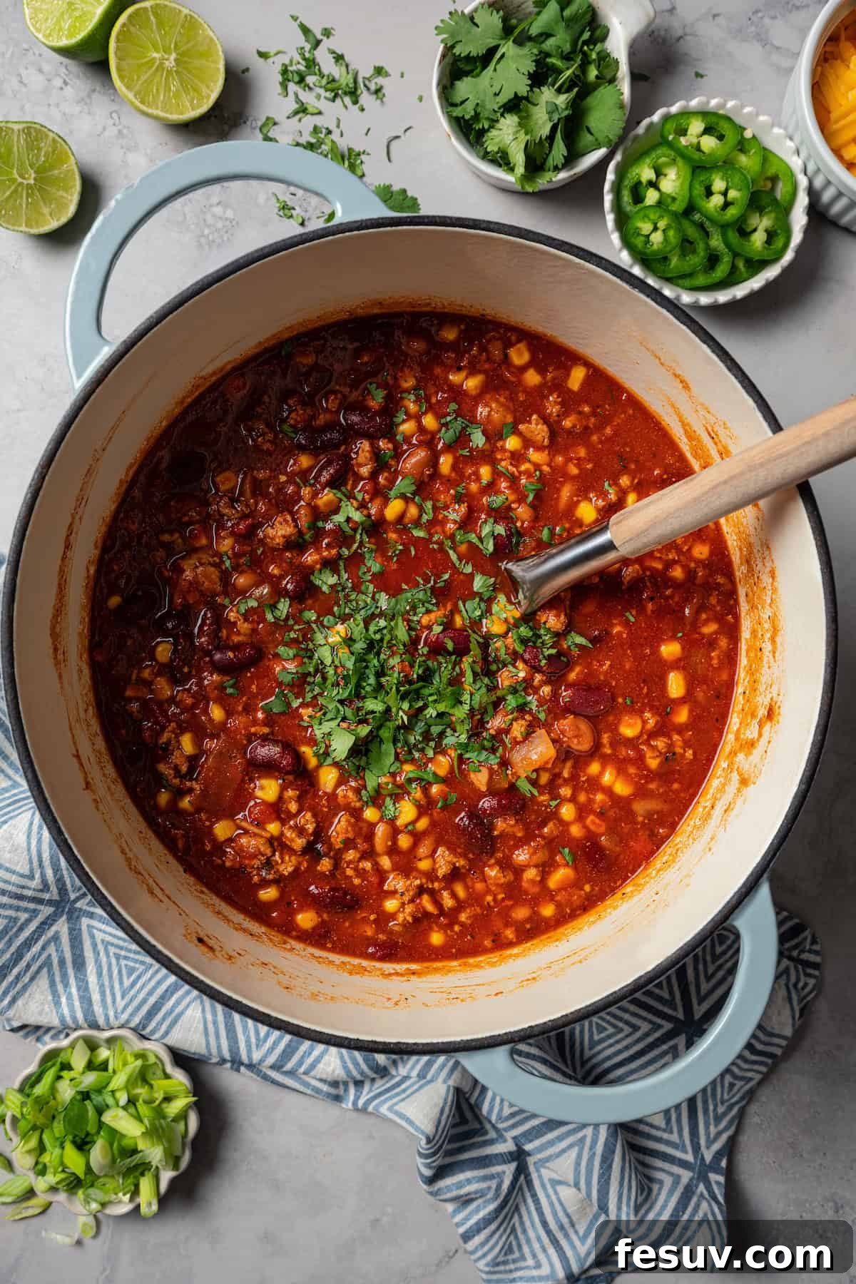 The BEST turkey chili recipe with juicy ground turkey, veggies, beans, and the perfect blend of spices. Great for weeknights and game days! Finished turkey chili garnished with fresh cilantro in a large pot, ready to be served.
