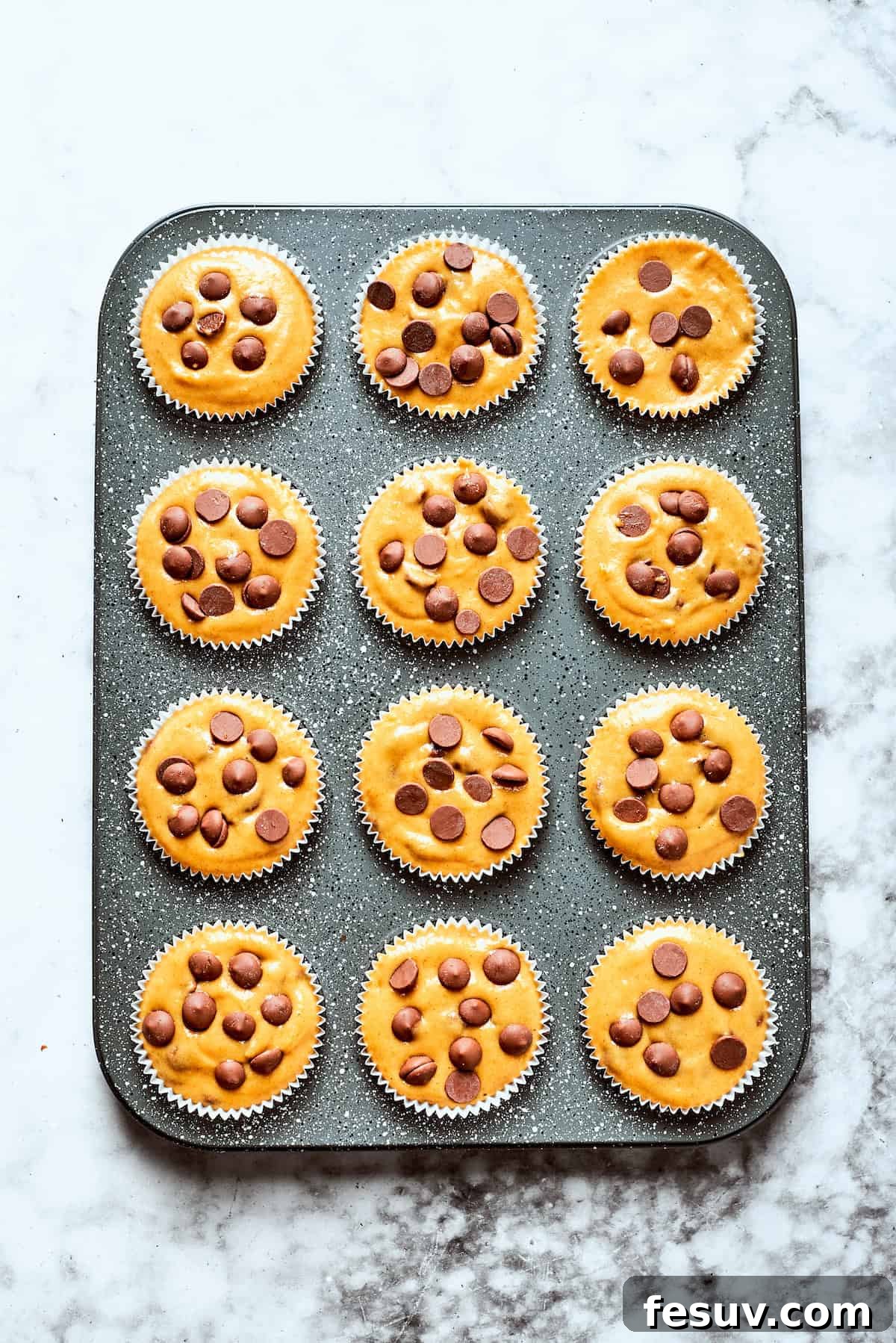 Pumpkin chocolate chip muffin batter in a muffin tin.