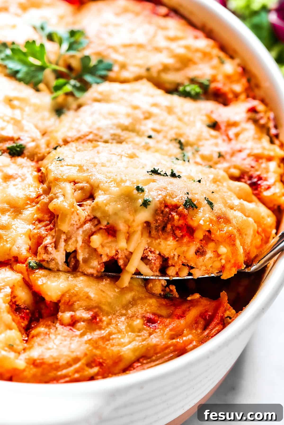 Serving Baked Million Dollar Spaghetti A generous serving of baked Million Dollar Spaghetti being spooned out from the casserole dish, showing its layered cheesy goodness.