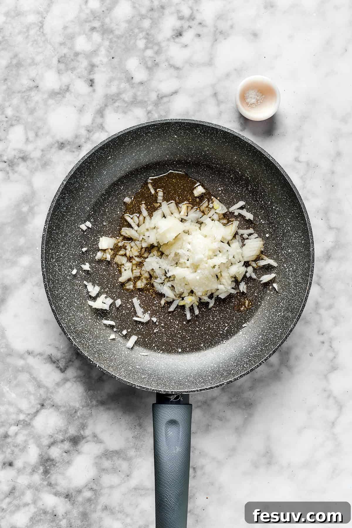 Sautéing Onions for the Meat Sauce Diced onions in a skillet, ready to be sautéed until translucent.