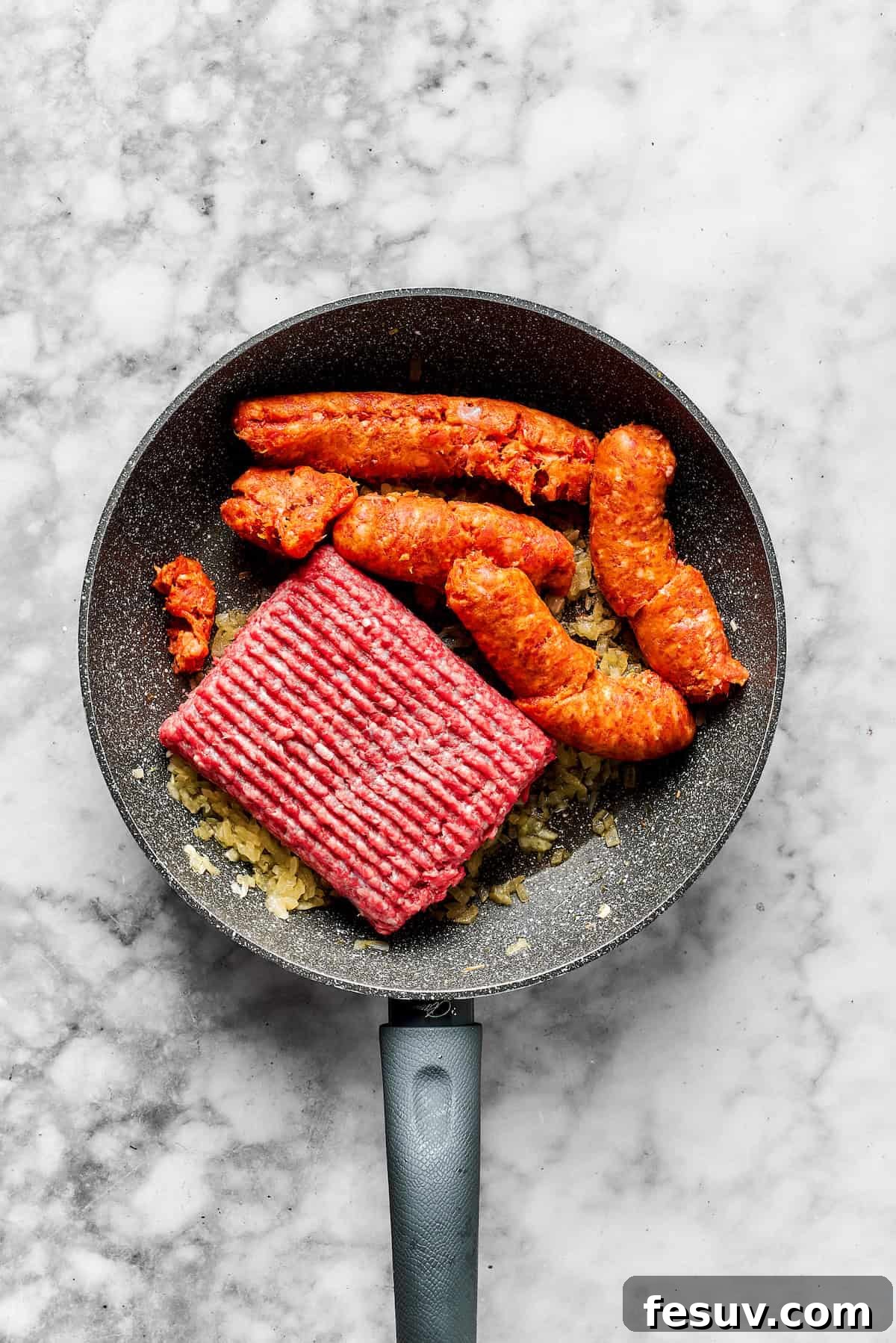 Browning Ground Meats for Rich Flavor Adding ground beef and Italian sausage to the skillet with sautéed onions, preparing to brown the meat.