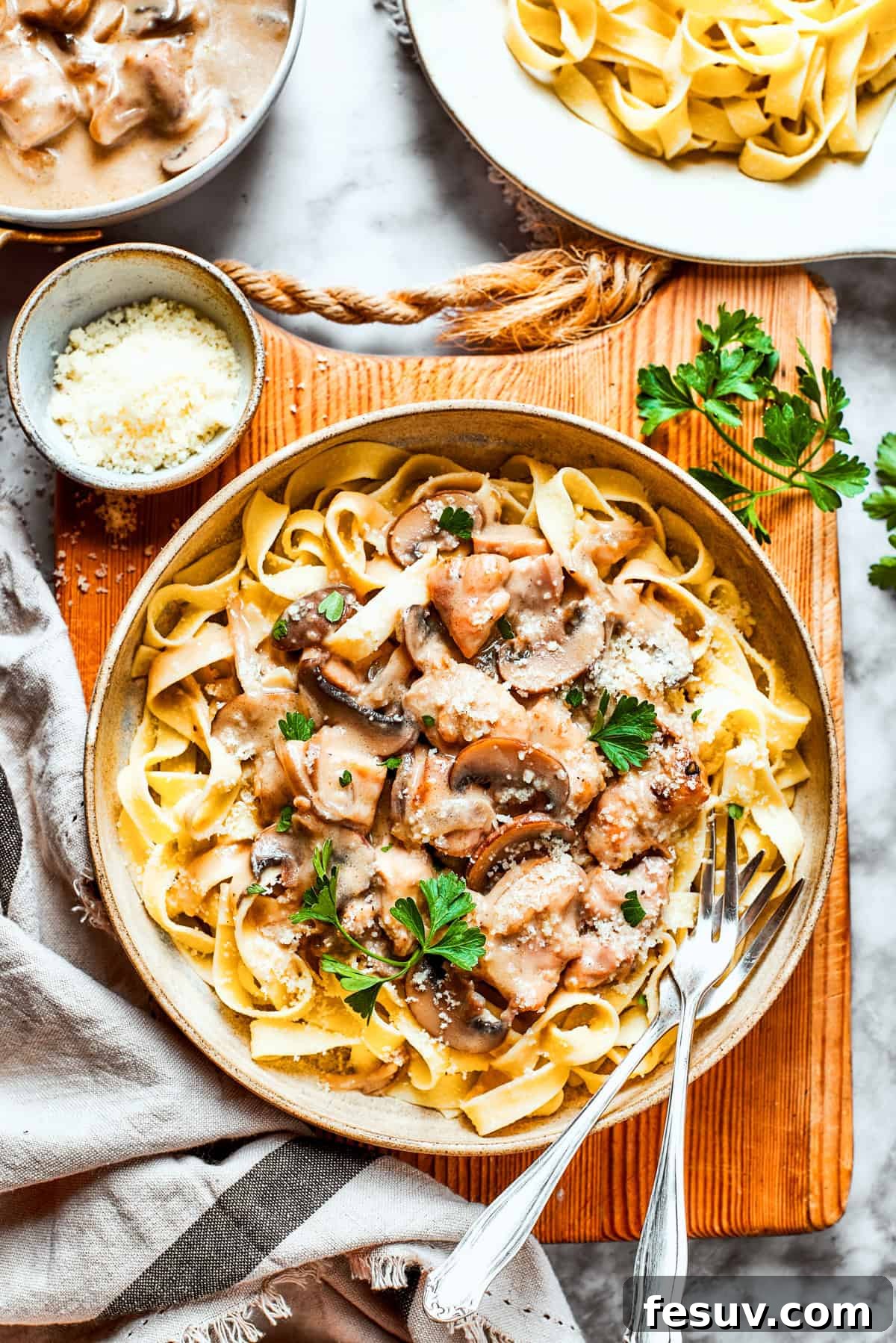 A rustic, inviting bowl of creamy Chicken Marsala Fettuccine, artfully placed on a weathered wooden board, highlighting the rich texture and delicious appeal of the dish.
