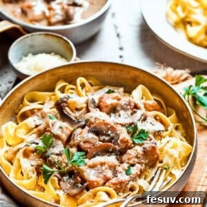 A close-up bowl of creamy Chicken Marsala Fettuccine, showing tender chicken pieces, sautéed mushrooms, and golden noodles coated in a rich Marsala sauce.