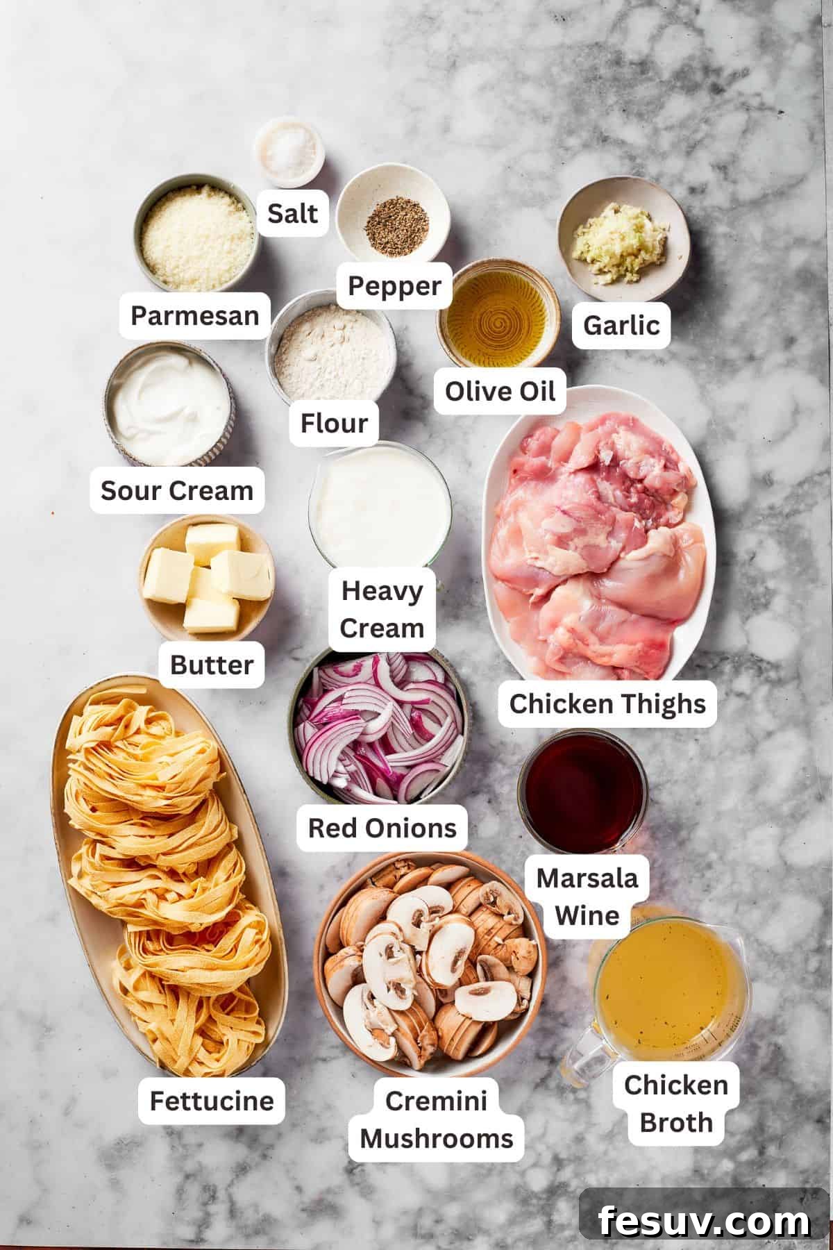 A vibrant flat lay of all the fresh and essential ingredients required to prepare a delicious Chicken Marsala Fettuccine, neatly arranged on a rustic wooden board.