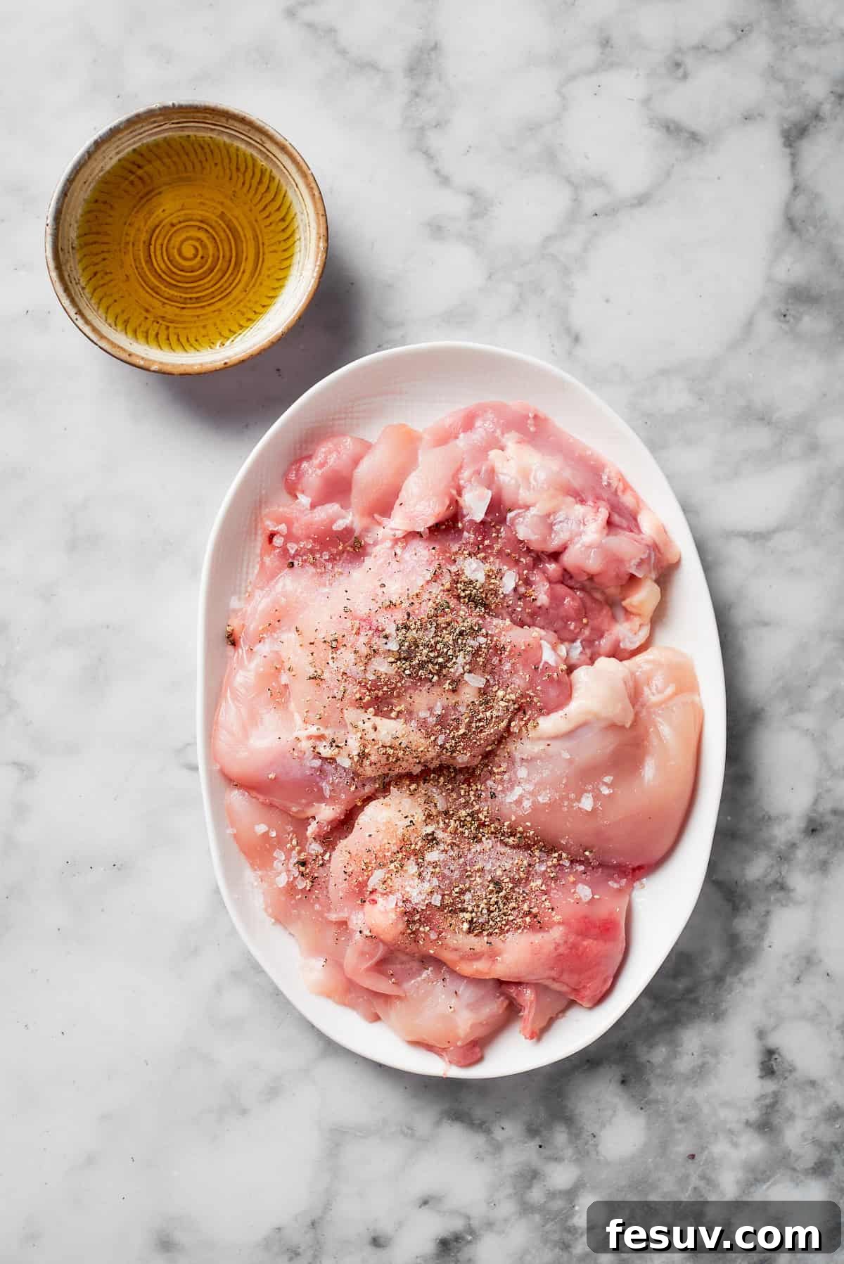 Raw chicken breasts generously seasoned with salt and pepper, ready for searing.