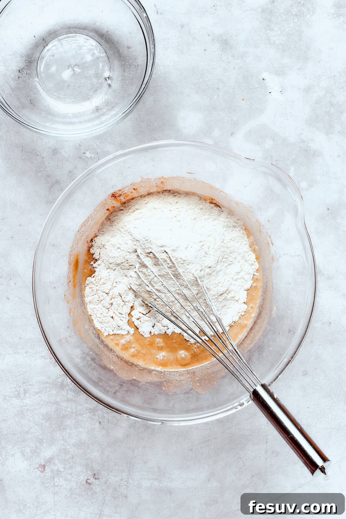 The combined dry ingredients are gradually whisked into the wet batter, ensuring a smooth, lump-free mixture.