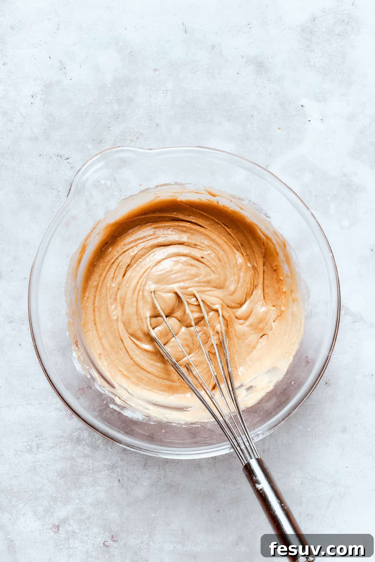 The donut batter is gently mixed in a bowl until it is smooth and just combined, avoiding overmixing.