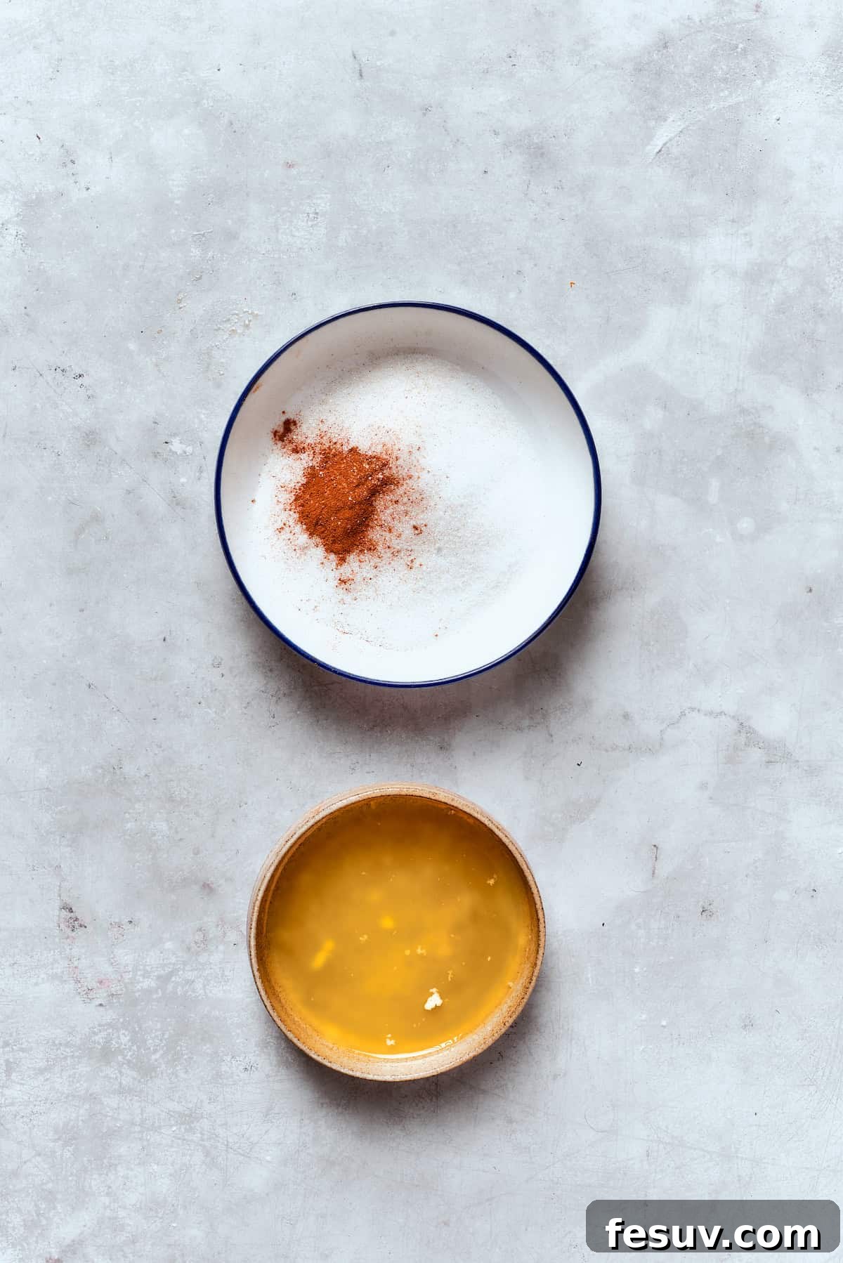 Two bowls are shown: one containing melted butter and the other holding a mixture of granulated sugar and cinnamon, prepared for the donut topping.