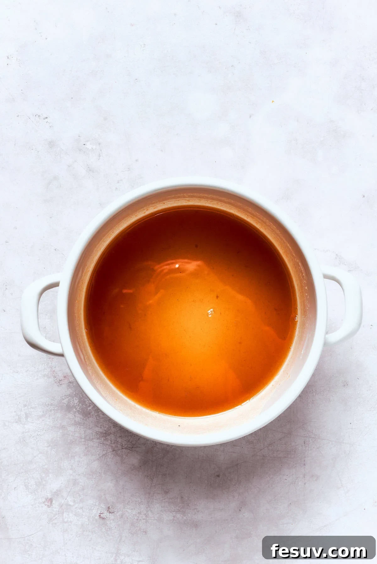 A pot of apple cider simmering on the stove, visibly reducing and concentrating its flavor.