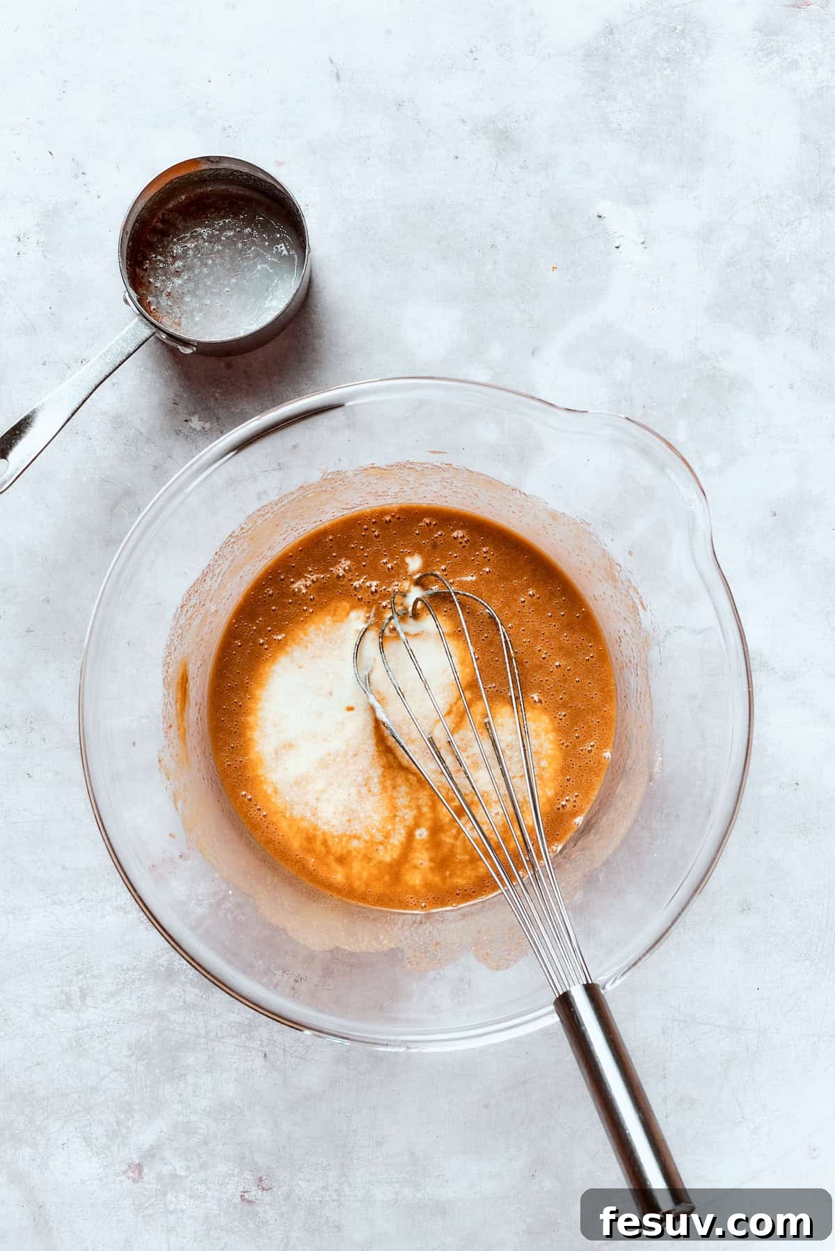 Buttermilk is gently poured and whisked into the wet ingredients, creating a smooth and cohesive batter base.