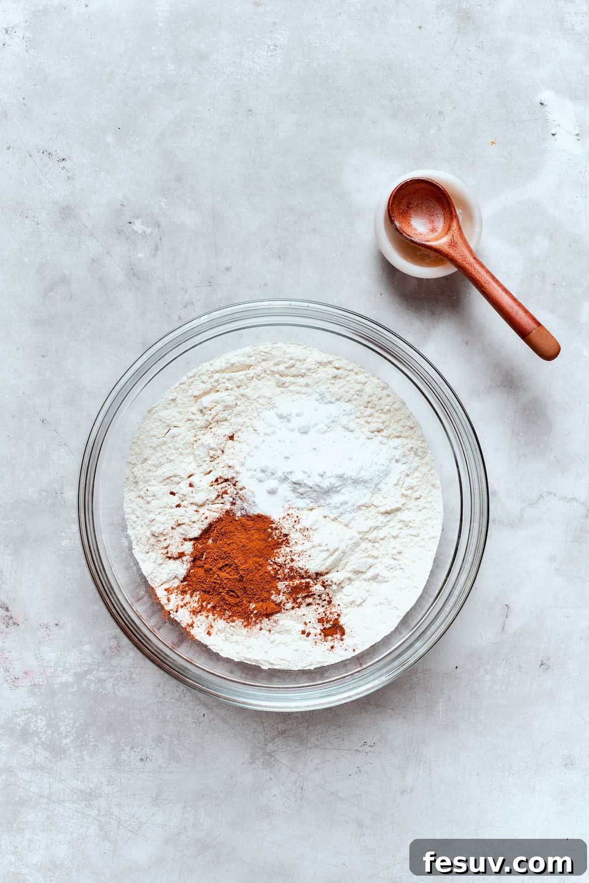 A separate bowl holds all the dry ingredients: flour, baking powder, baking soda, salt, and various warm spices, perfectly combined.