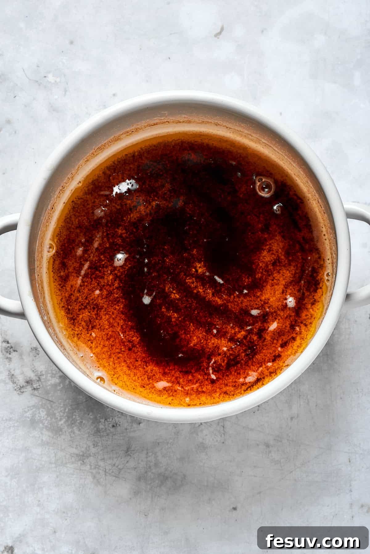 A pot of deeply browned butter with golden amber milk solids at the bottom, ready to be cooled.