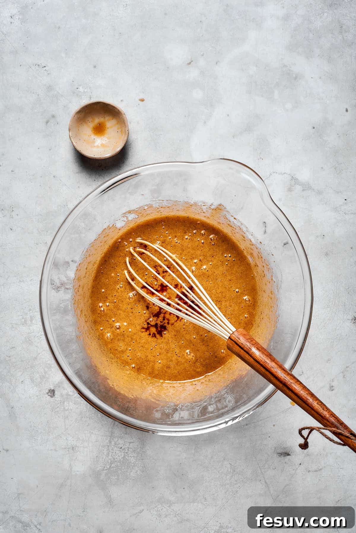 The cookie dough mixture with eggs and vanilla being whisked until smooth and fully incorporated.