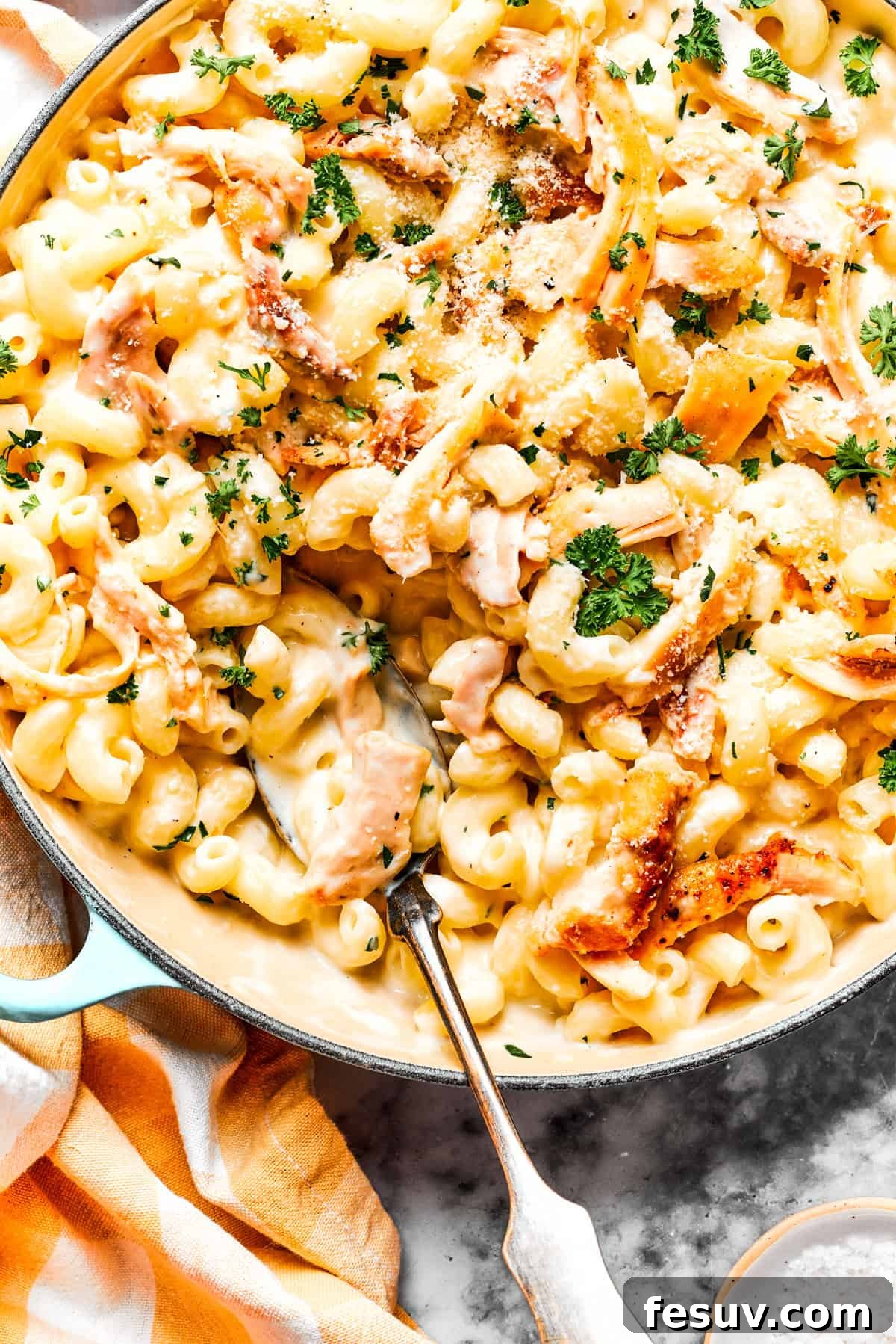 A close-up of the delectable Creamy Garlic Parmesan Chicken Pasta in a skillet. Close-up image of creamy garlic parmesan chicken pasta in a skillet, with a serving spoon resting inside the skillet, showcasing the rich sauce and tender chicken pieces.