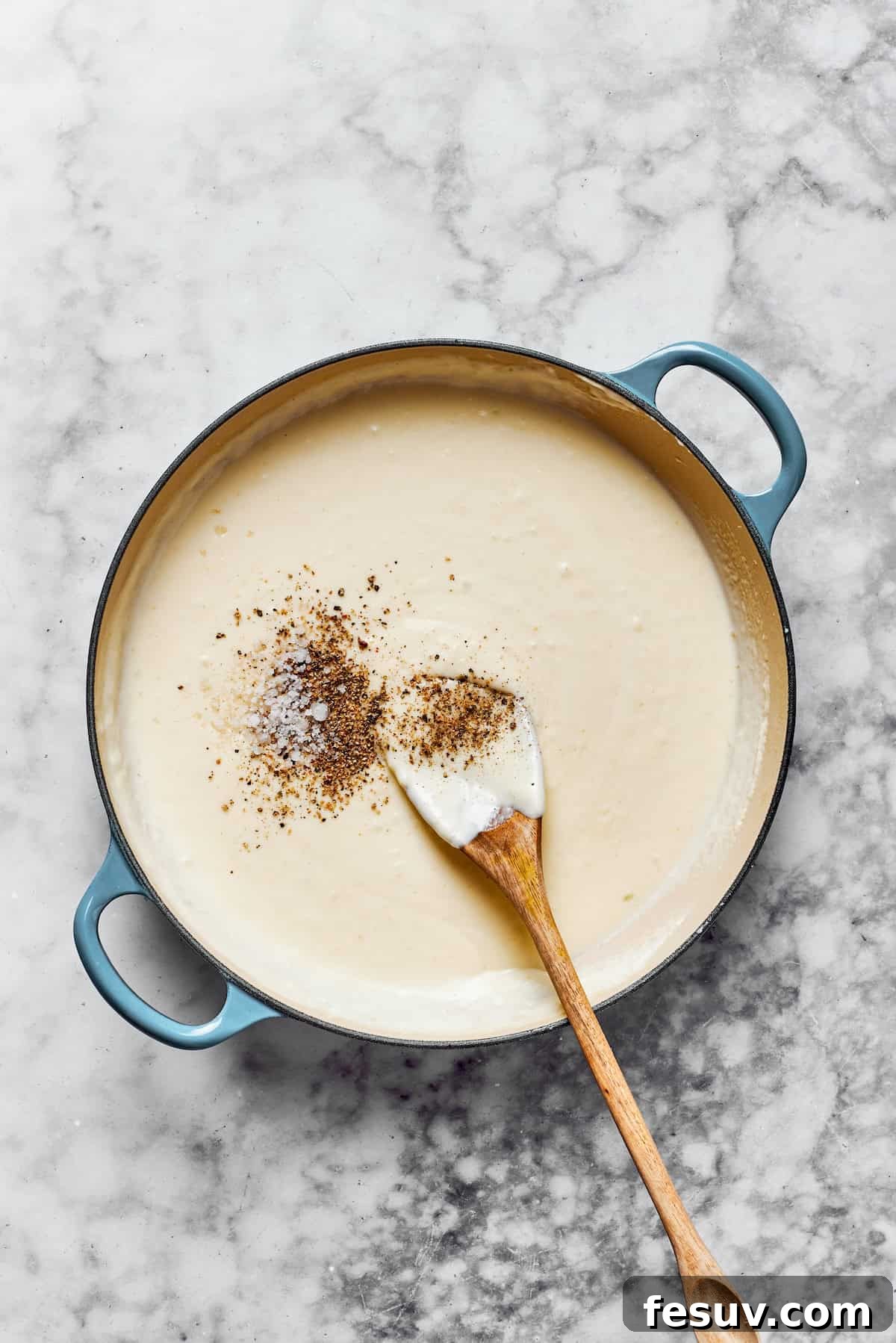 Season the creamy sauce meticulously to achieve perfect flavor balance. A hand adding salt and freshly ground black pepper to a creamy pasta sauce in a pan, meticulously seasoning it to taste before the final ingredients are incorporated.