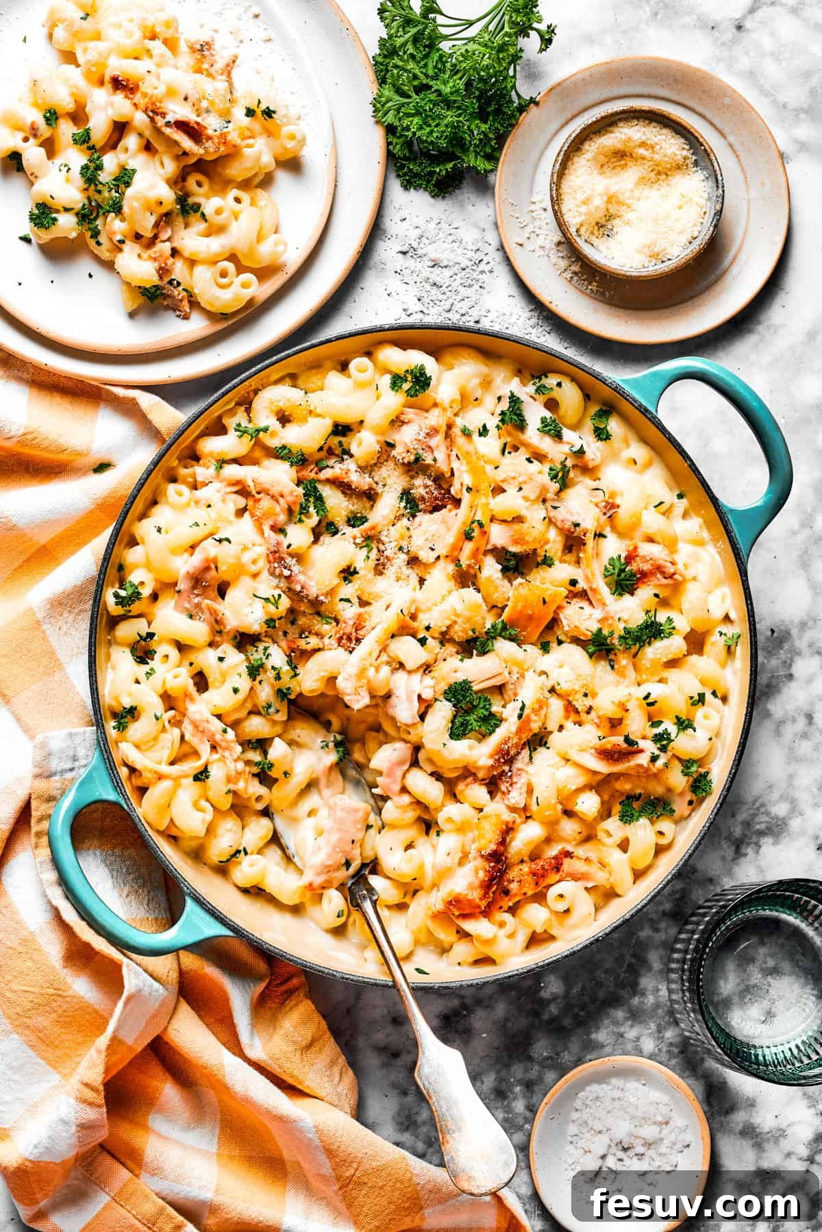 Creamy Garlic Parmesan Chicken Pasta served in a pot and plated for guests. Overhead photo of a large pot filled to the brim with creamy garlic parmesan chicken pasta, with a single, perfectly portioned serving plated beautifully next to it, ready to be enjoyed.