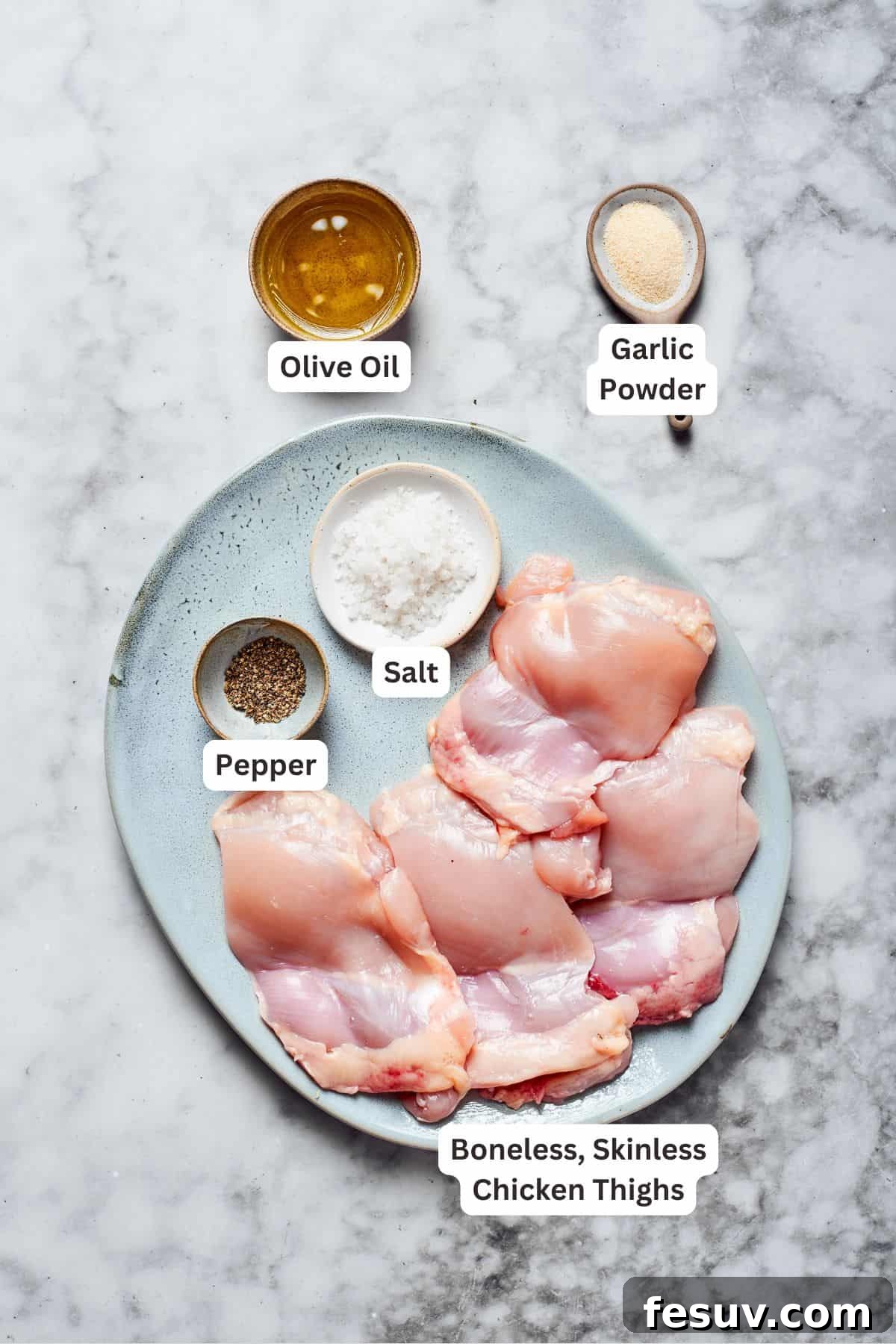 Essential ingredients for roasting flavorful chicken to perfection. Ingredients for perfectly roasted chicken, including boneless skinless chicken thighs, olive oil, and a selection of seasonings, meticulously laid out on a clean counter.