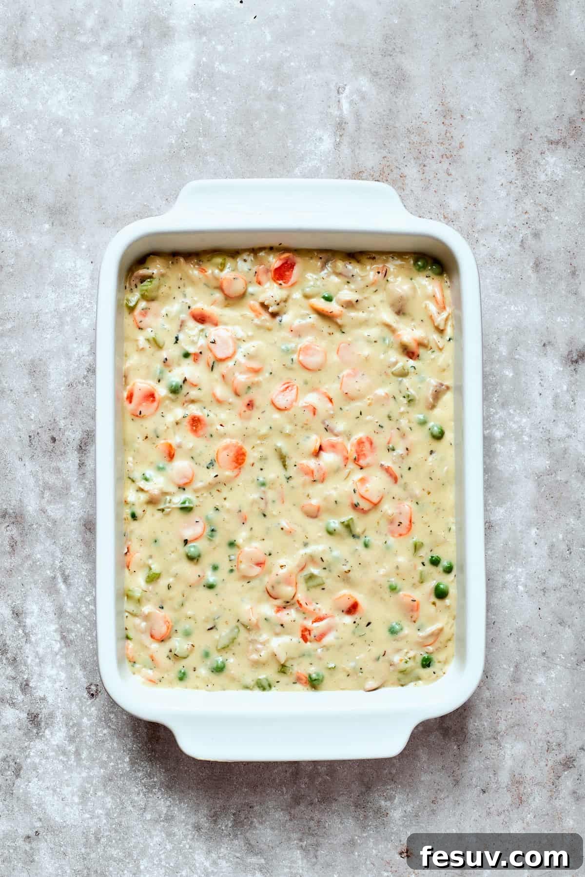 Chicken pot pie casserole is everything you love about the classic comfort food, baked under fluffy buttermilk biscuits instead of pie crust! The finished chicken pot pie filling generously poured into a prepared baking dish, ready for biscuit topping.