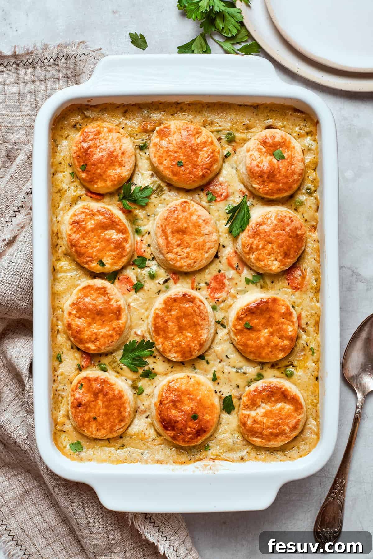 Chicken pot pie casserole is everything you love about the classic comfort food, baked under fluffy buttermilk biscuits instead of pie crust! A freshly baked chicken pot pie casserole, golden brown and bubbly, in a white baking dish.