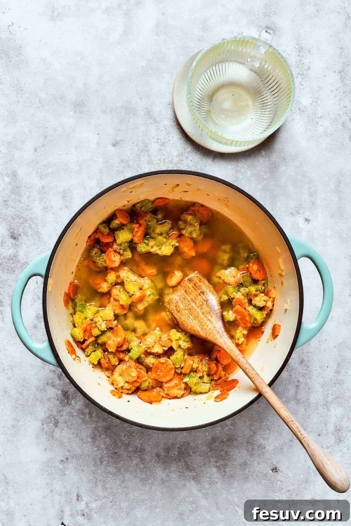 Chicken pot pie casserole is everything you love about the classic comfort food, baked under fluffy buttermilk biscuits instead of pie crust! Chicken stock being poured into a large pot with sautéed vegetables and flour.
