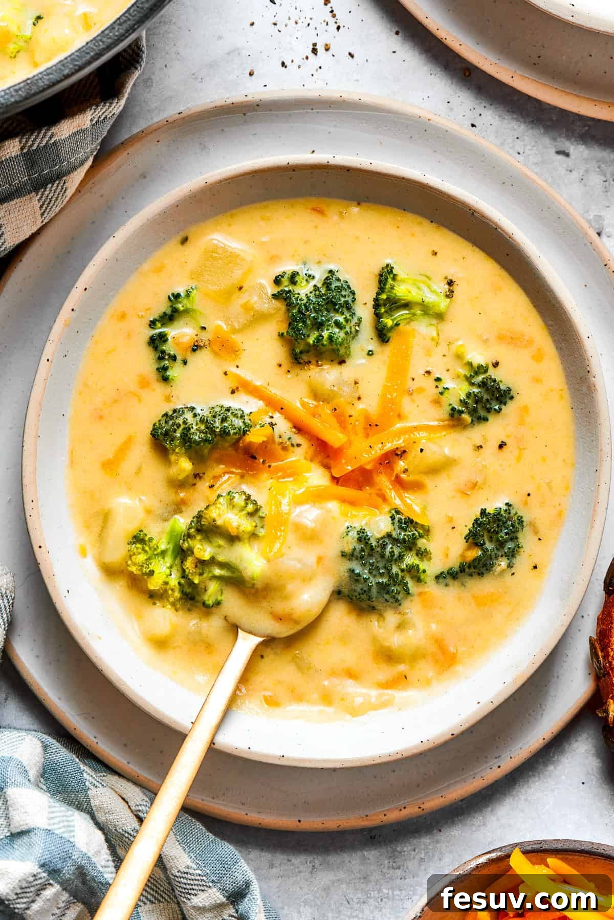Broccoli cheese soup served in a bowl and garnished with shredded cheese and broccoli florets.
