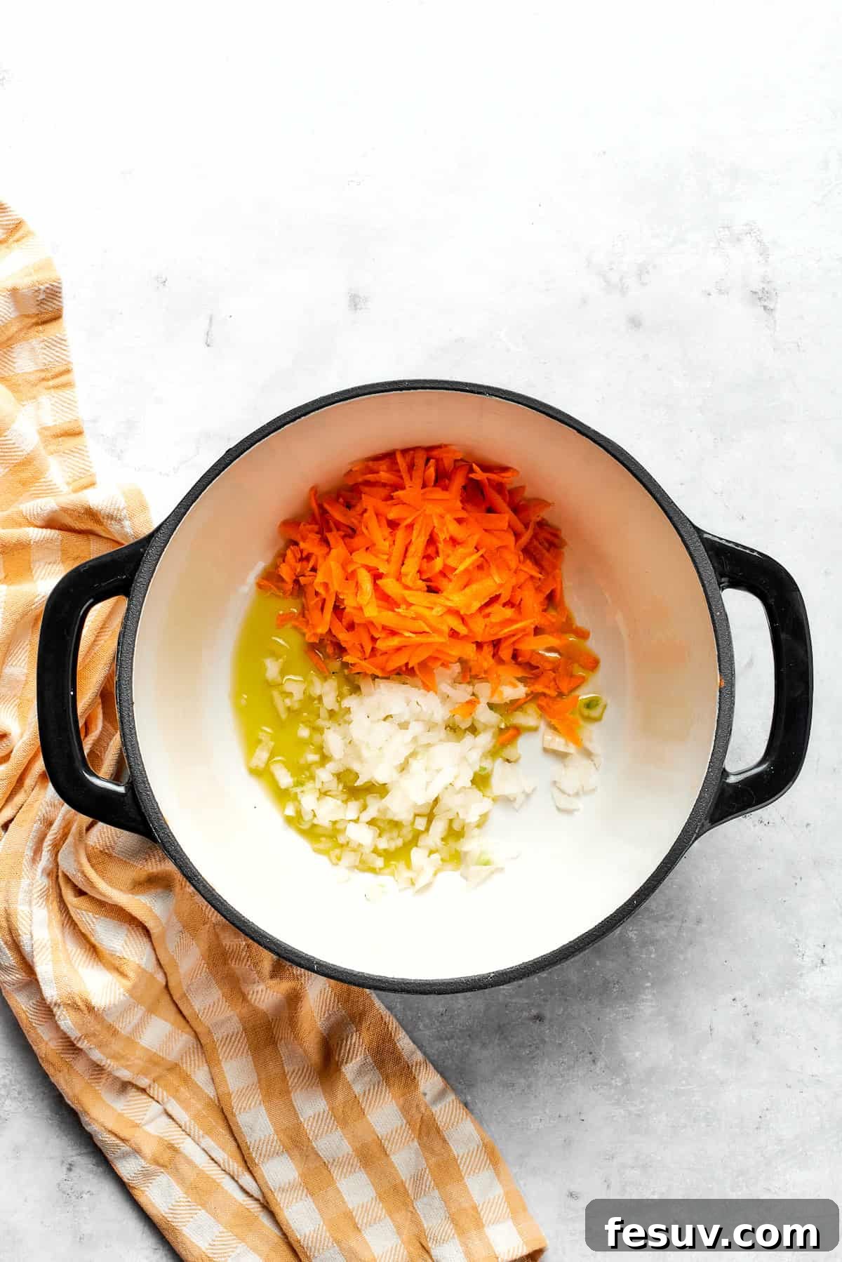 Cooking carrots and onion in a pot.
