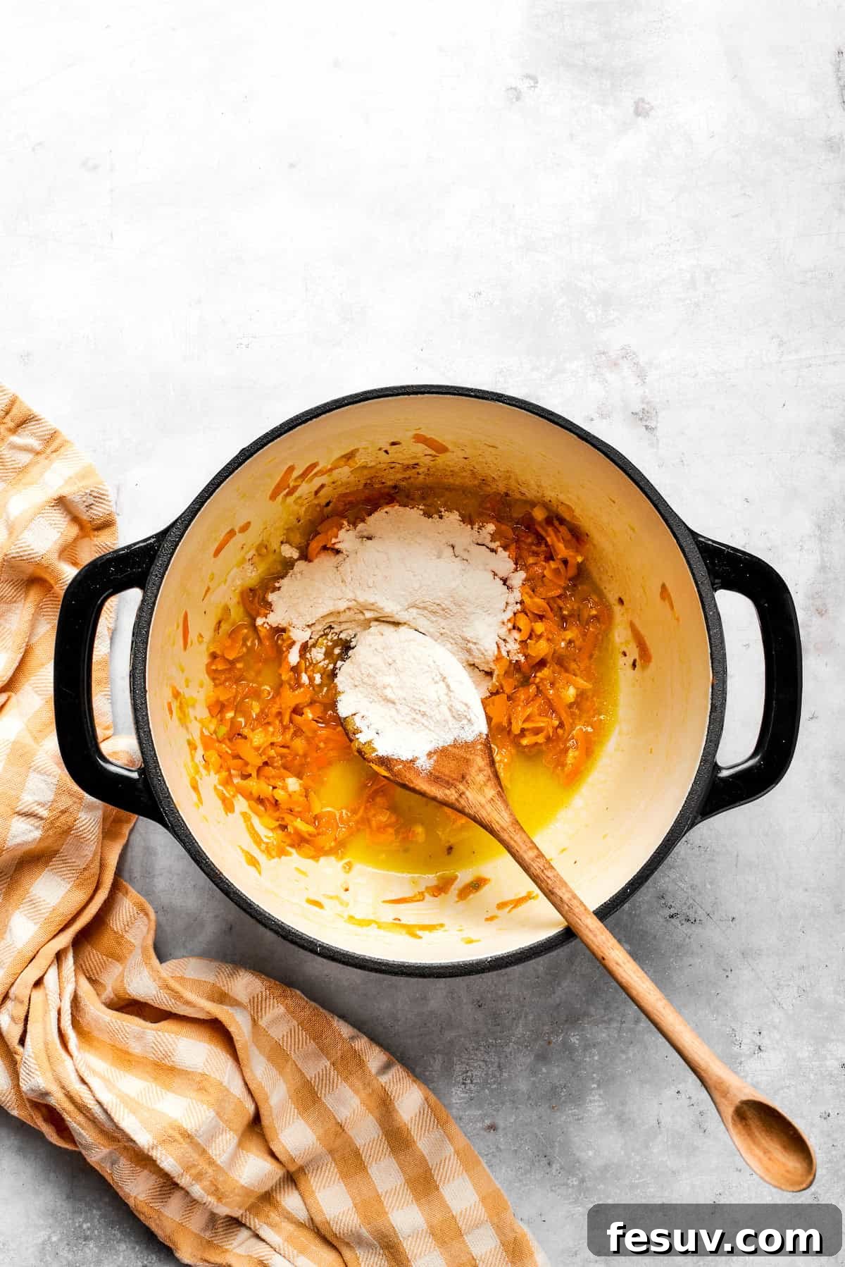 Adding flour to a pot with carrots and butter.