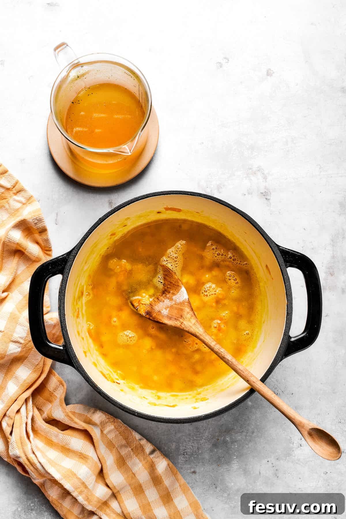 Stirring broth into a pot with carrots and roux.