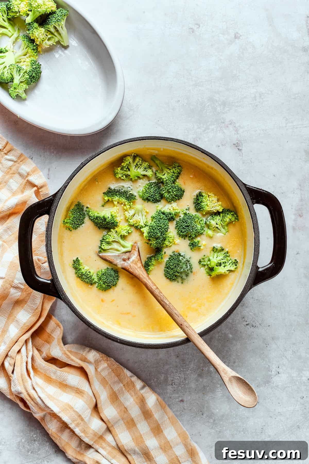 Stirring broccoli florets into a pot of soup.