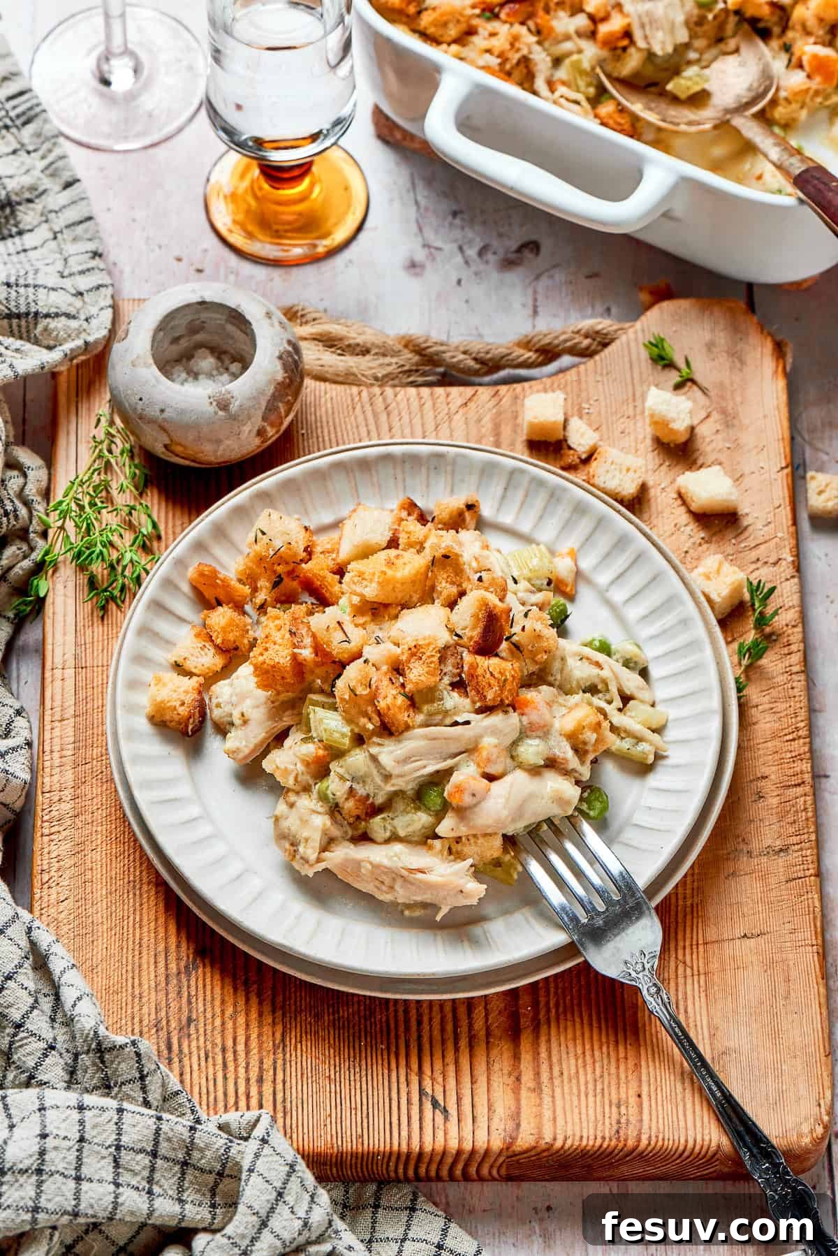 A serving of chicken stuffing casserole on a white plate, showing the layers of filling and golden stuffing.