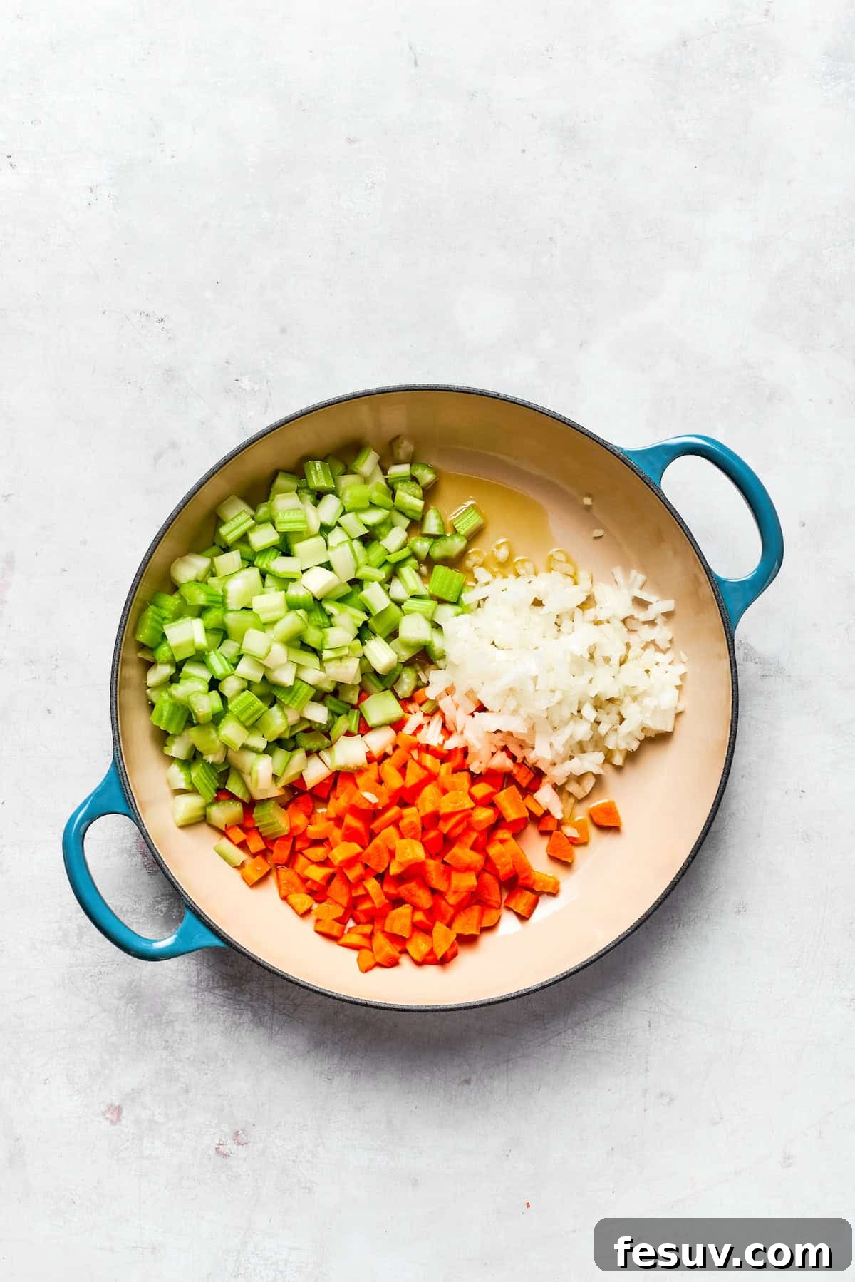 Diced onions, carrots, and celery cooking in a pot with olive oil.