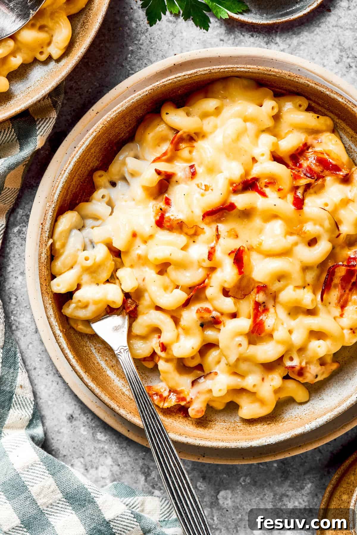 A perfectly portioned serving of creamy bacon macaroni and cheese in a bowl, with a fork ready to dig in.