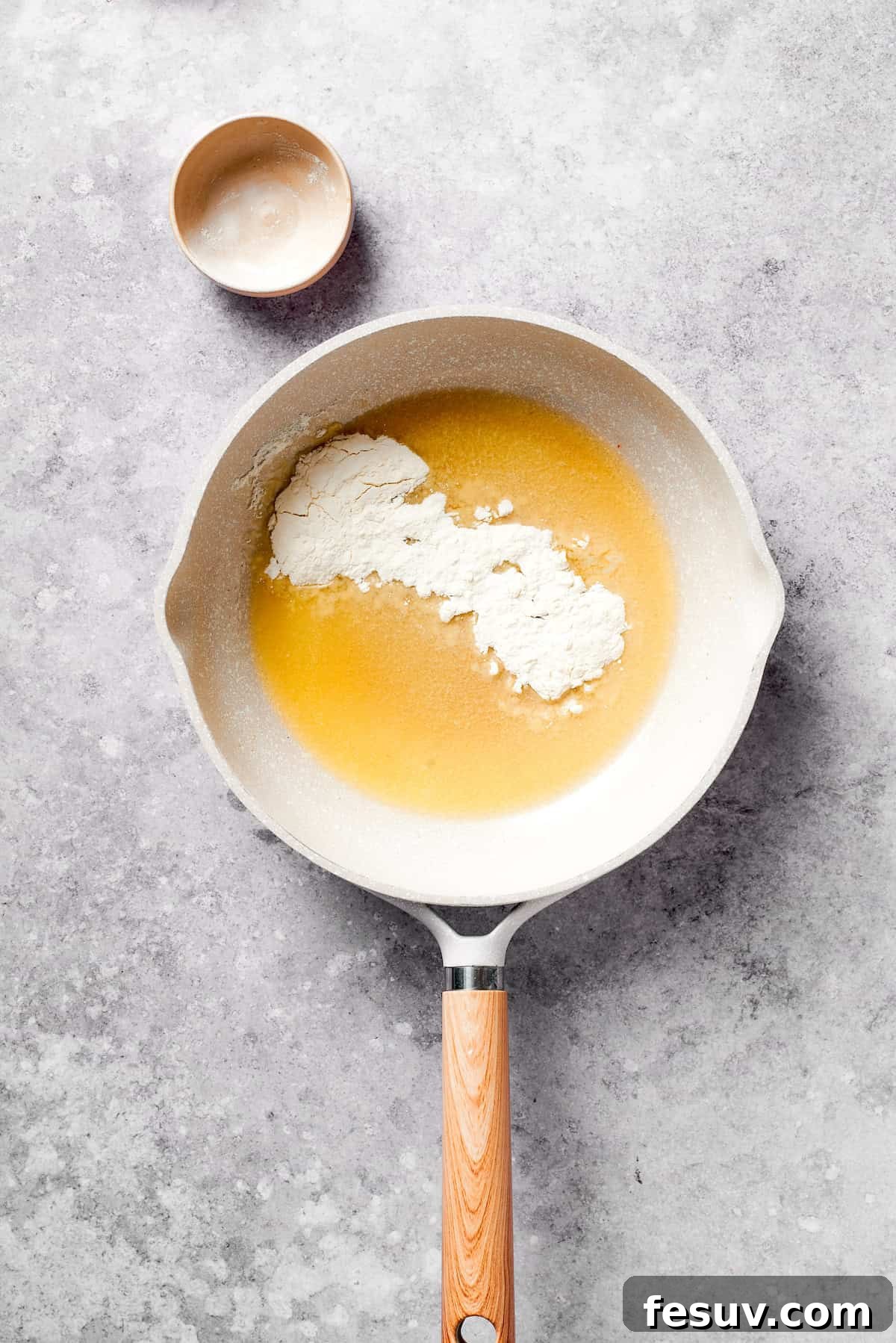 Butter melting in a large skillet, with flour being whisked in to create a rich roux for the cheese sauce.