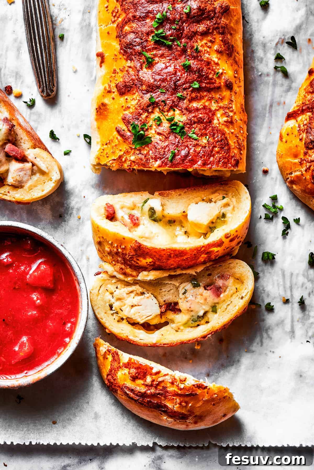 A sliced Costco chicken bake revealing its creamy chicken, bacon, and cheese filling, with a bowl of dressing on the side.