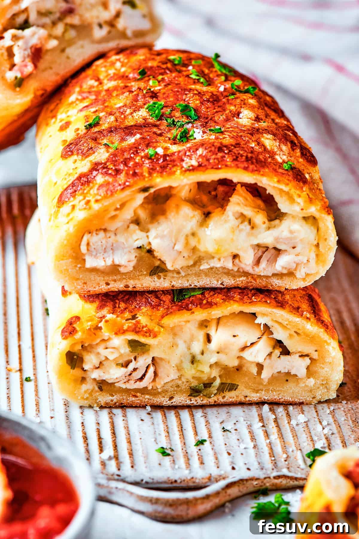 A Costco chicken bake cut in half, showcasing its rich, creamy filling of chicken, bacon, and cheese.