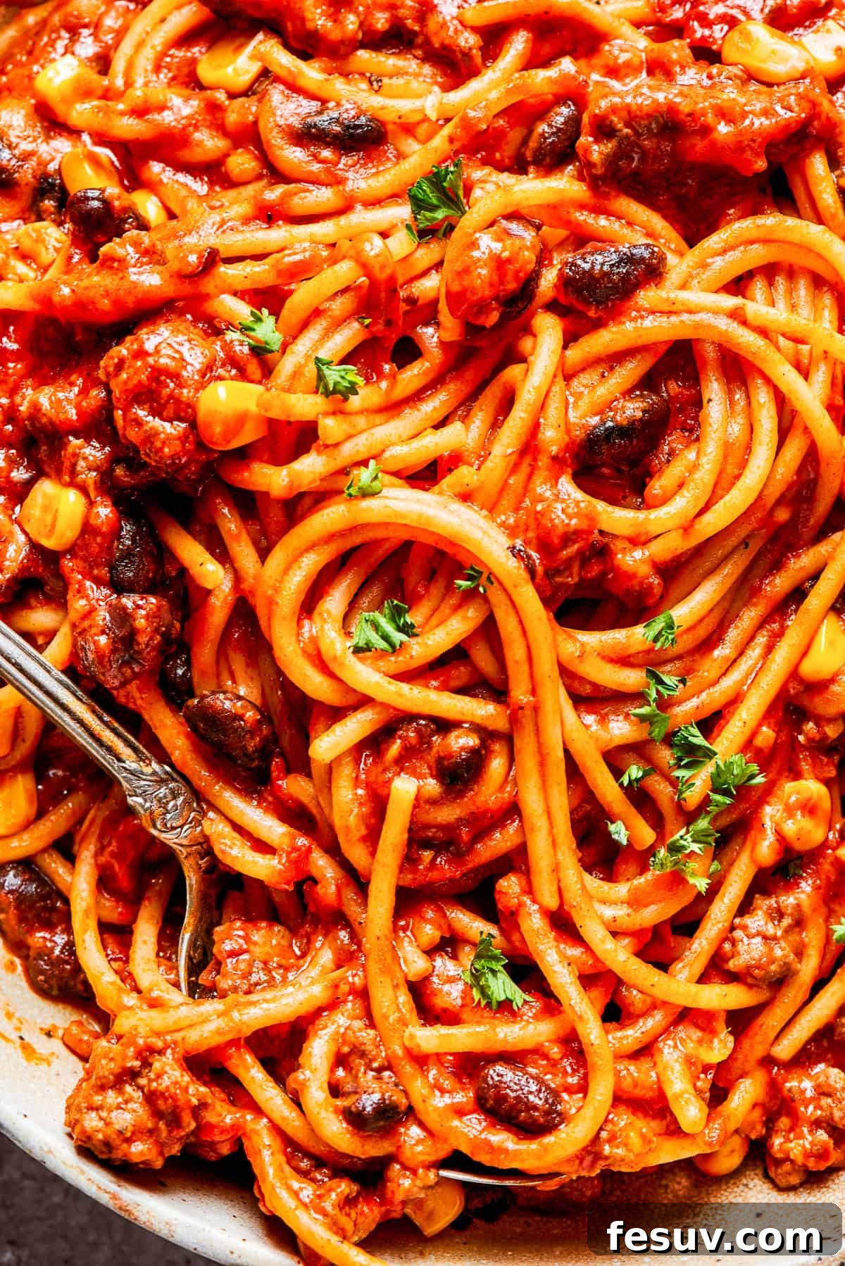 Delicious Mexican spaghetti, showcasing the texture and vibrant colors of the ingredients. A close-up view of Mexican spaghetti tossed with rich tomato sauce, black beans, and corn.
