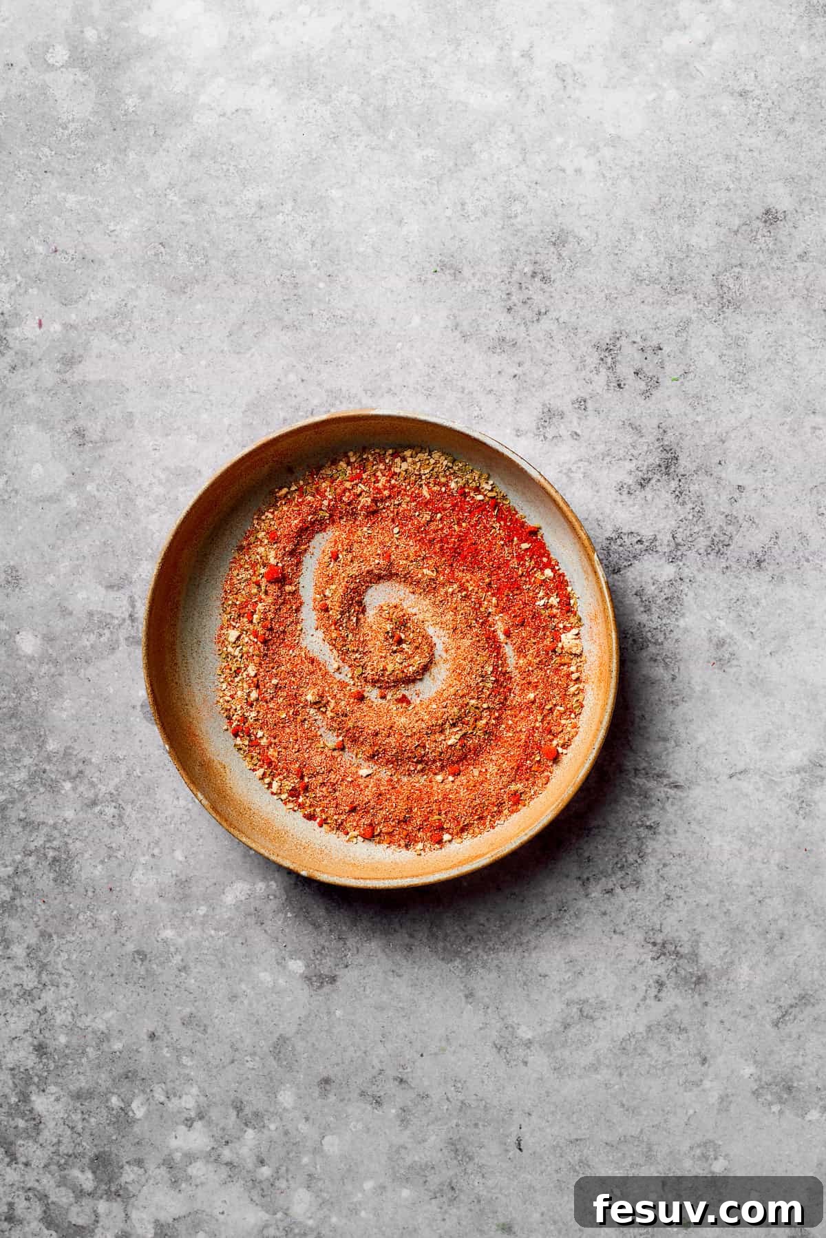 A blend of aromatic spices for homemade taco seasoning. A small bowl containing a vibrant mix of taco seasoning spices.