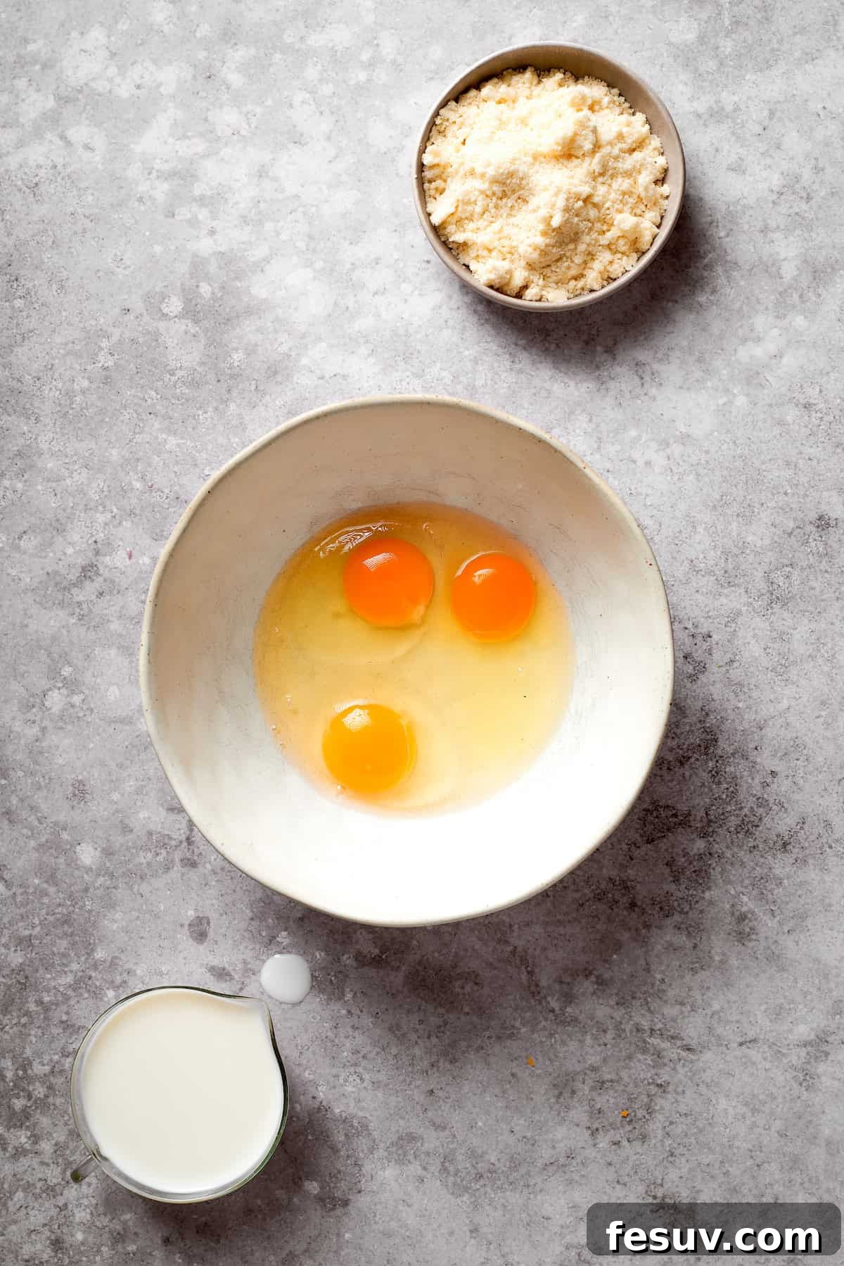 Three large eggs in a mixing bowl, ready to be whisked for the biscuit crust batter.