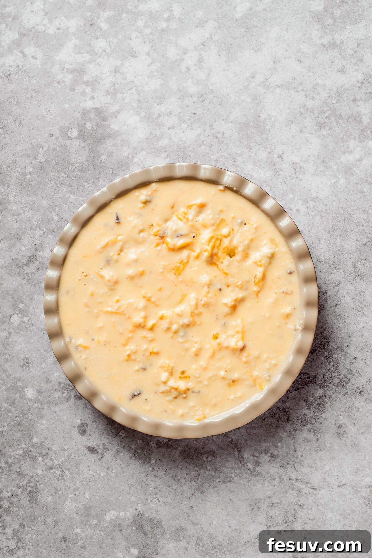 The cheeseburger pie in a pie dish, with the biscuit topping spread, placed in an oven ready for baking.