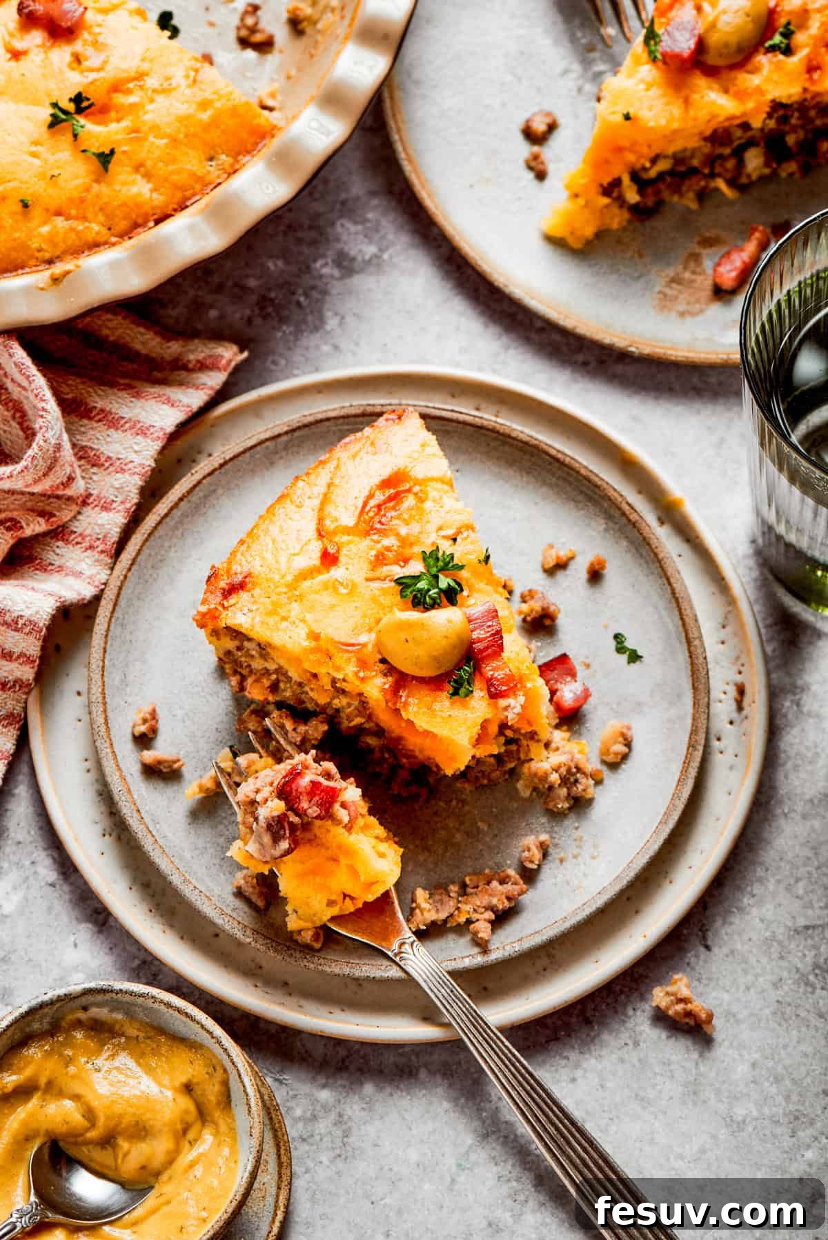 A perfectly portioned slice of golden-brown cheeseburger pie served on a clean dinner plate, with a fork resting beside it.