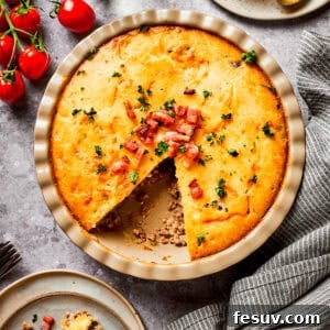 Overhead image of cheeseburger pie in a pie dish, with one wedge cut out.