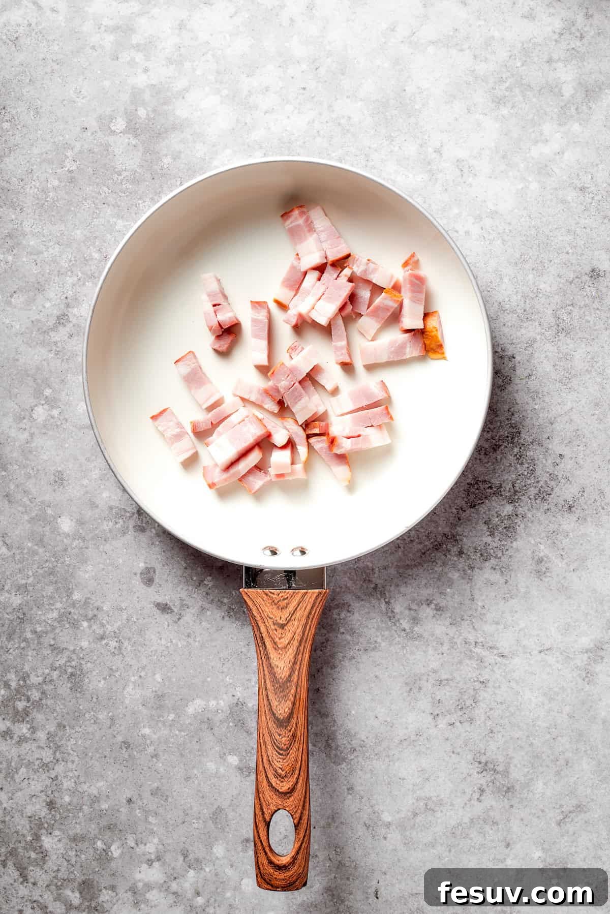 Chopped bacon sizzling in a hot skillet, ready to be cooked until crispy.